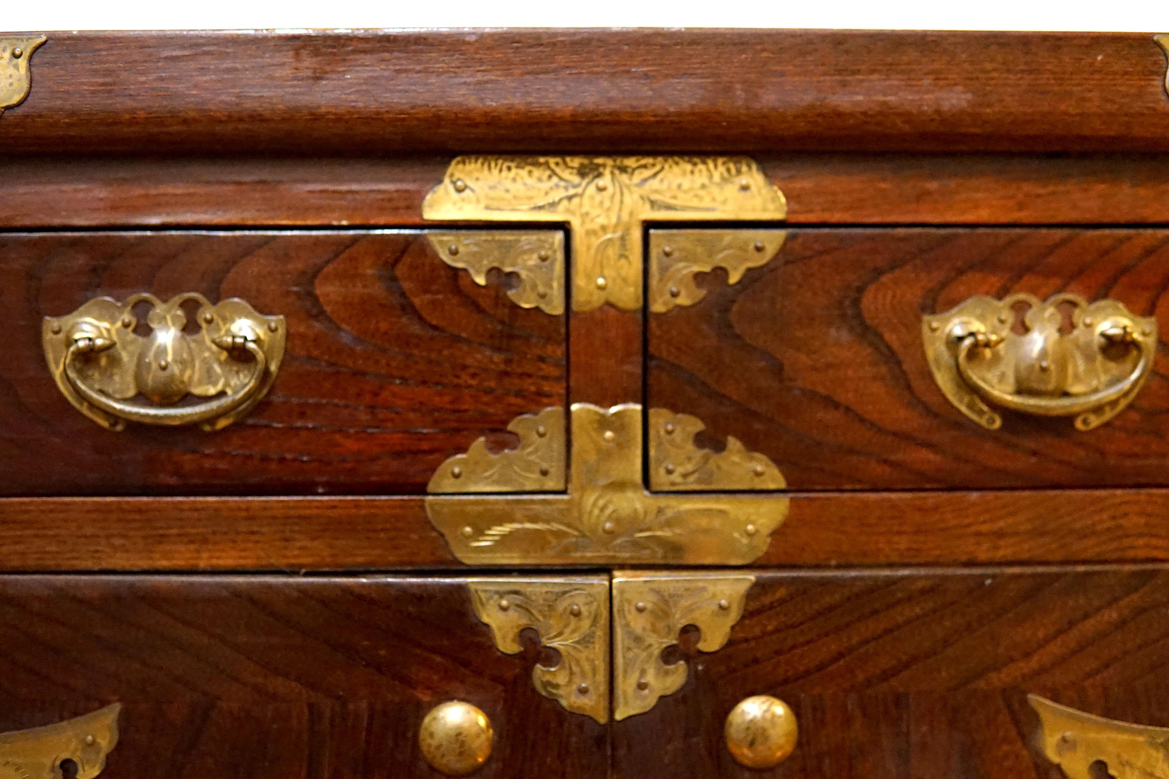 The patina on this elm wood tansu chest is reflective and deep. The brass also has had time to develop a deep patina that contrasts the elmwood. It mixes wonderfully with other periods and styles--a great accent piece. This majestic  tansu chest has