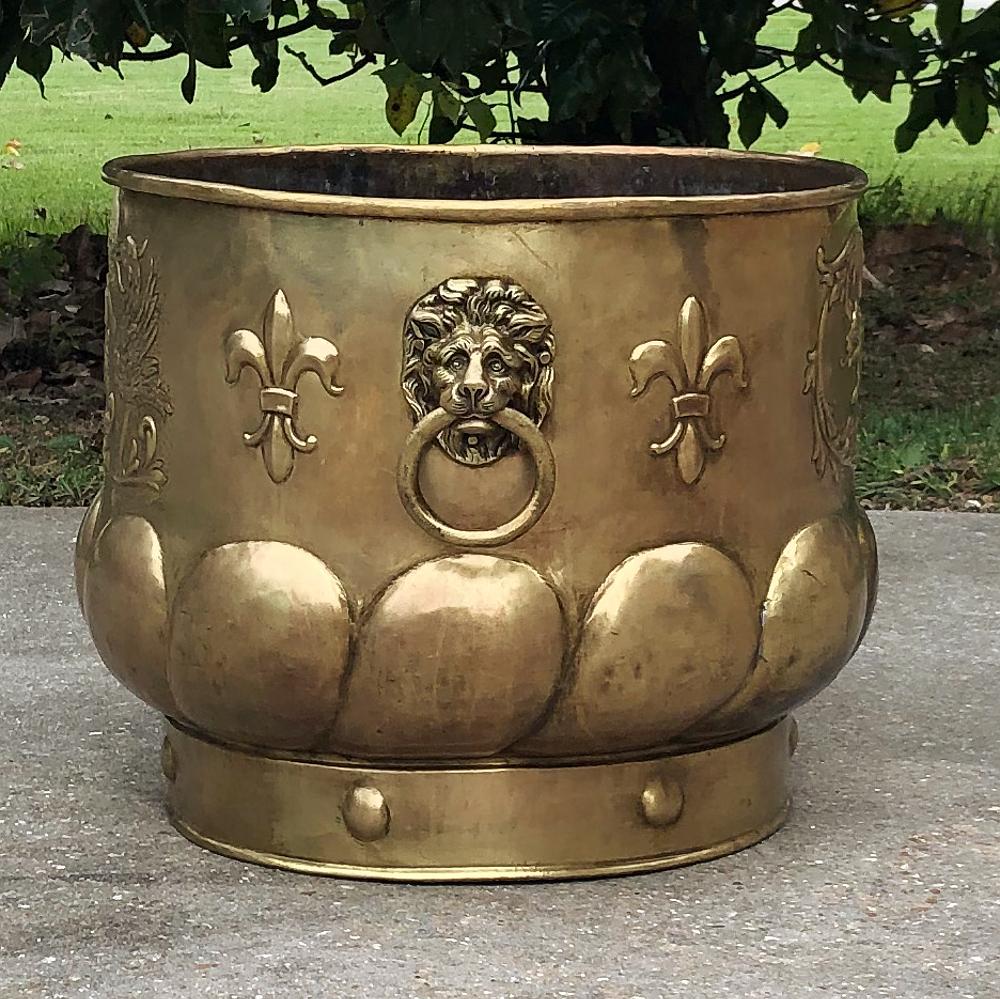 19th Century Embossed Brass Jardiniere is a splendid choice for creating an Old World ambiance, and features a lion embossed on both sides framed with foliates, and cast lions' heads on opposing sides with ring pulls for handles. Fleurs de lys