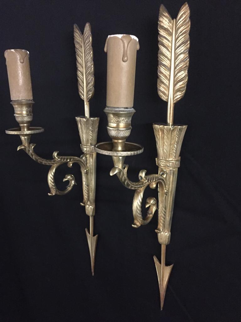 These stunning wall sconces display richness in true Empire style. 
This pair of ormolu French wall sconces, display an arrow which points down through the sheath, with beautiful detail in which the sheath is formed of many feathers, the candelabra