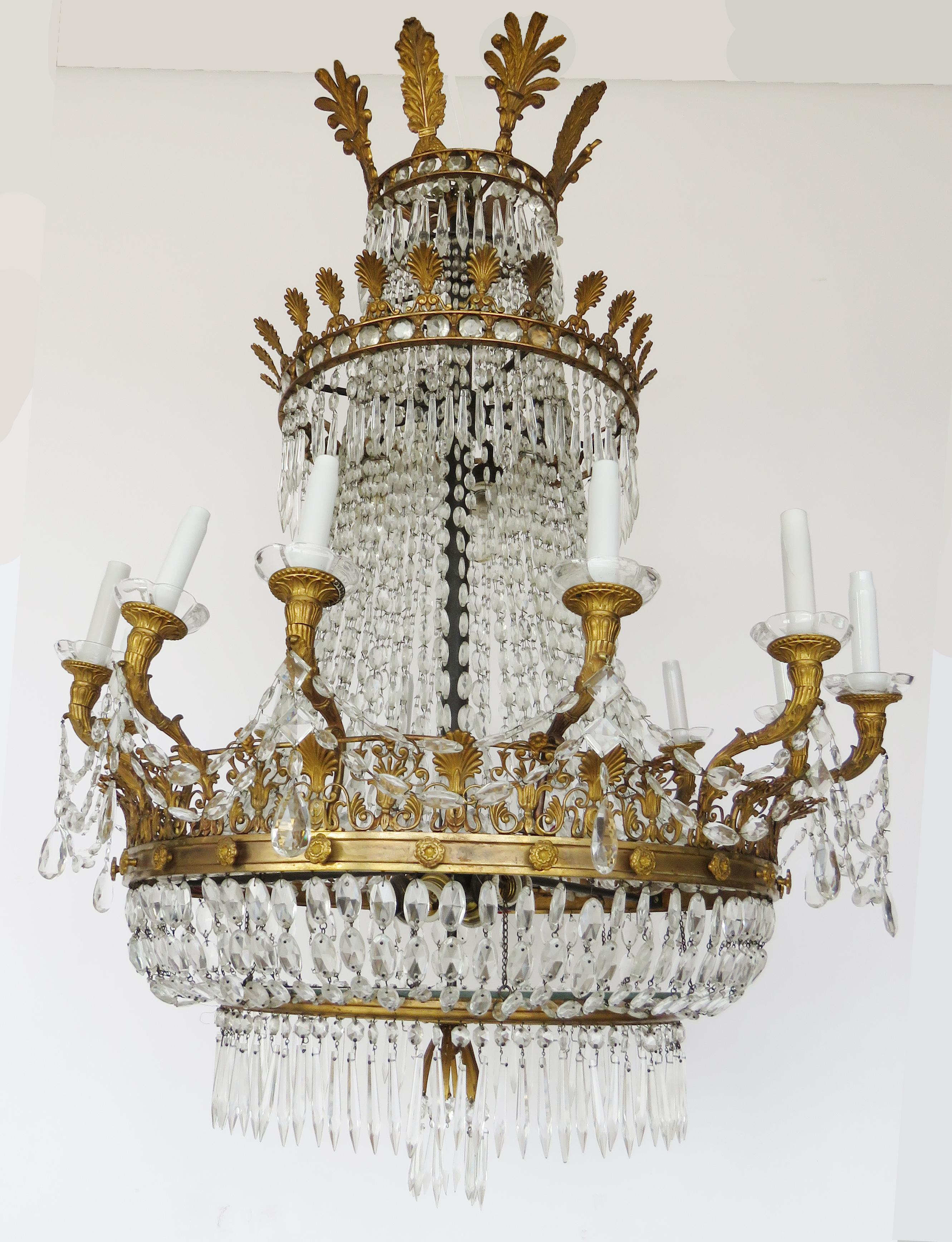 The gilt palmette cast corona over a ring suspended by faceted chains issuing palmettes hung with elongated tear drops and floriform candlecups the faceted chains intersecting the double crown
