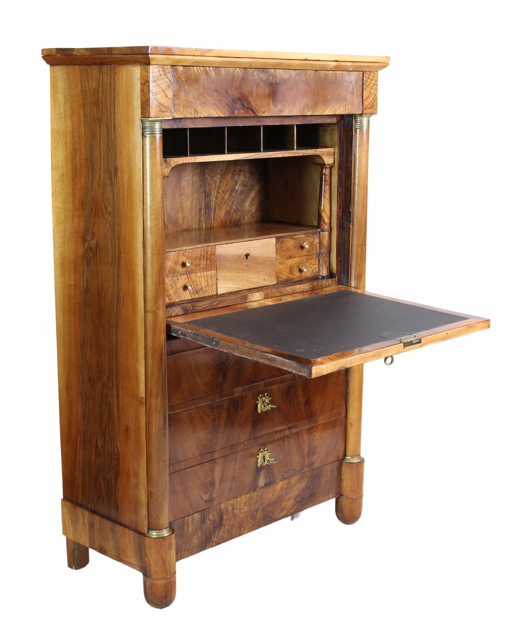 A beautiful small secretary made of walnut veneer and solid walnut from the Biedermeier / Empire period at the beginning of the 19th century. The secretary is covered on the outside with a beautiful walnut veneer pattern and made of solid walnut on