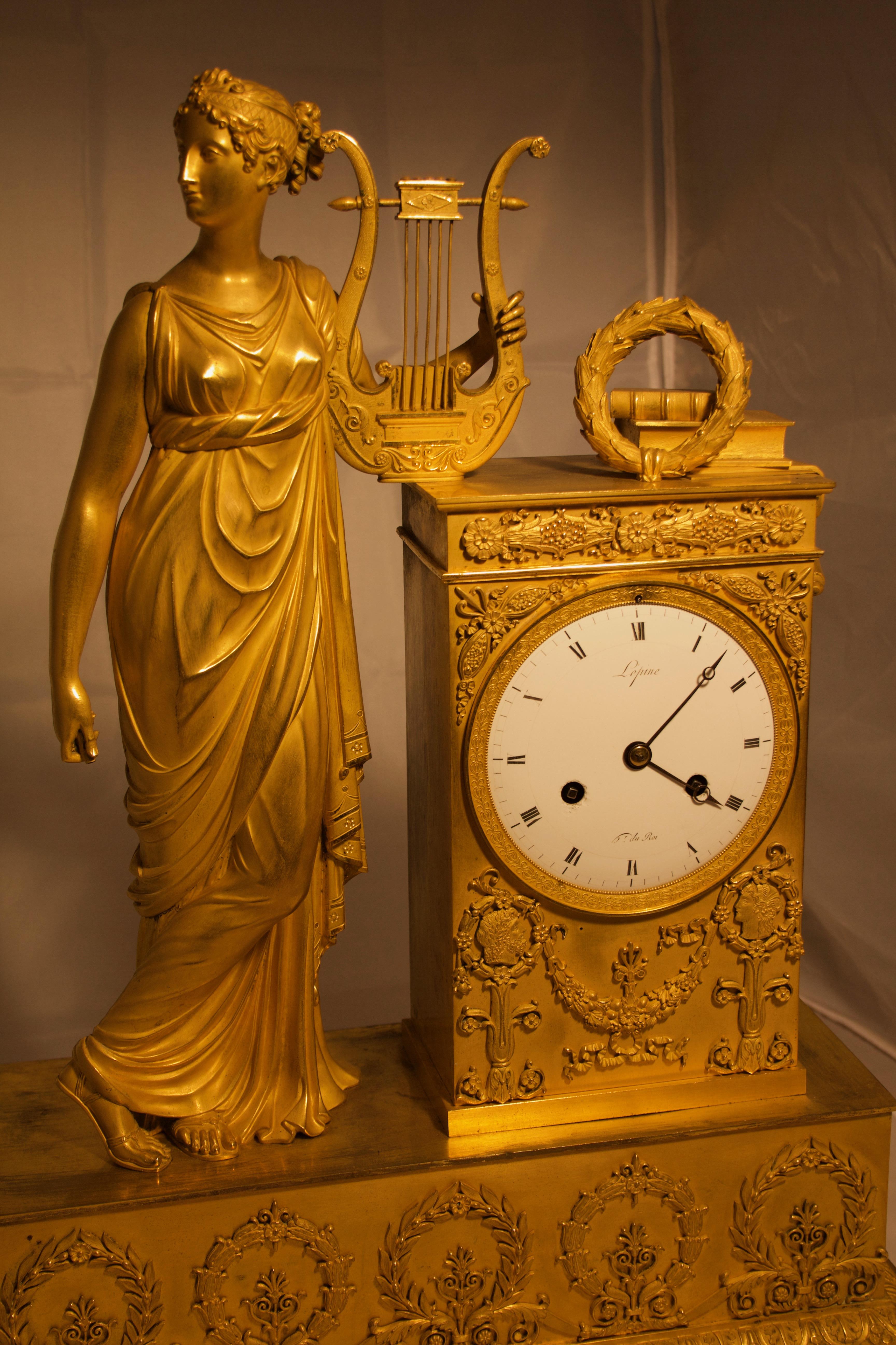 An important gilded bronze mantel clock from the early 19th century, signed by Lépine, France, the bronze statue depicts Tersicone, Musa della danza, with Arpa on a richly decorated plinth. White enamel dial with two charged forks, time and ring