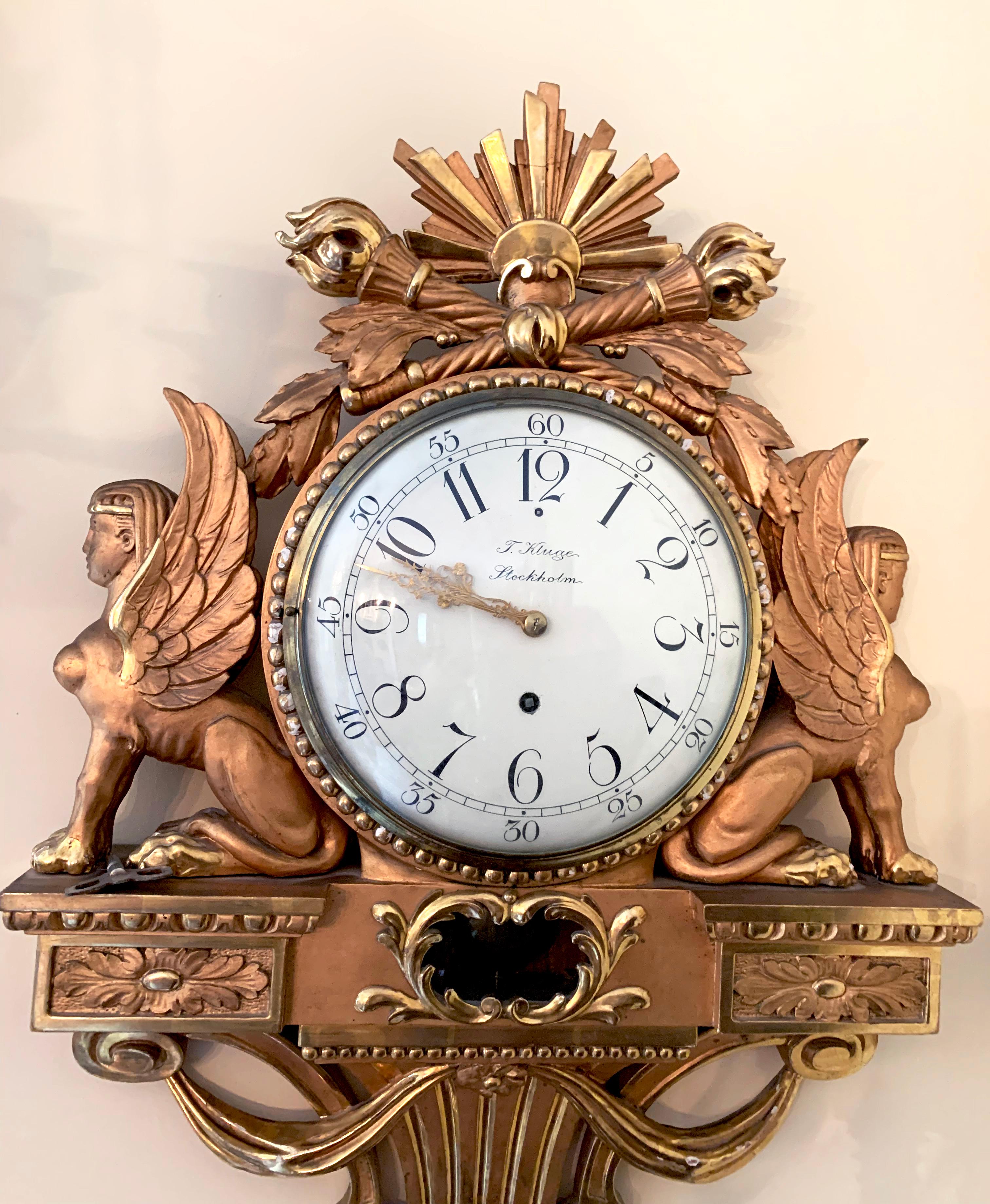 Une belle horloge Empire du 19ème siècle, dorée avec des sphinx assis de chaque côté. Signé avec T Kluge Stockholm au dos. 
Cadran bombé noir et blanc avec aiguilles dorées. Une pièce très décorative de l'époque en très bon état.