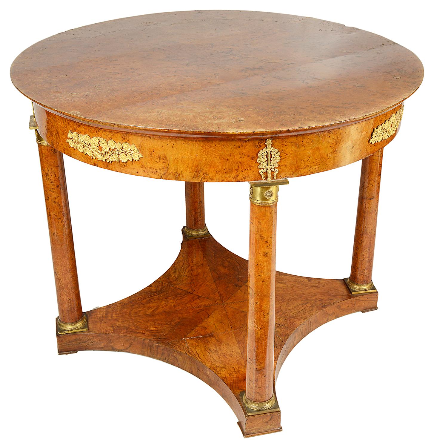 A good quality 19th century burr walnut French Empire influenced gueridon / centre table. Having classical gilded ormolu mounts to the frieze and capitals to the four circular supports that are united by a platform base.