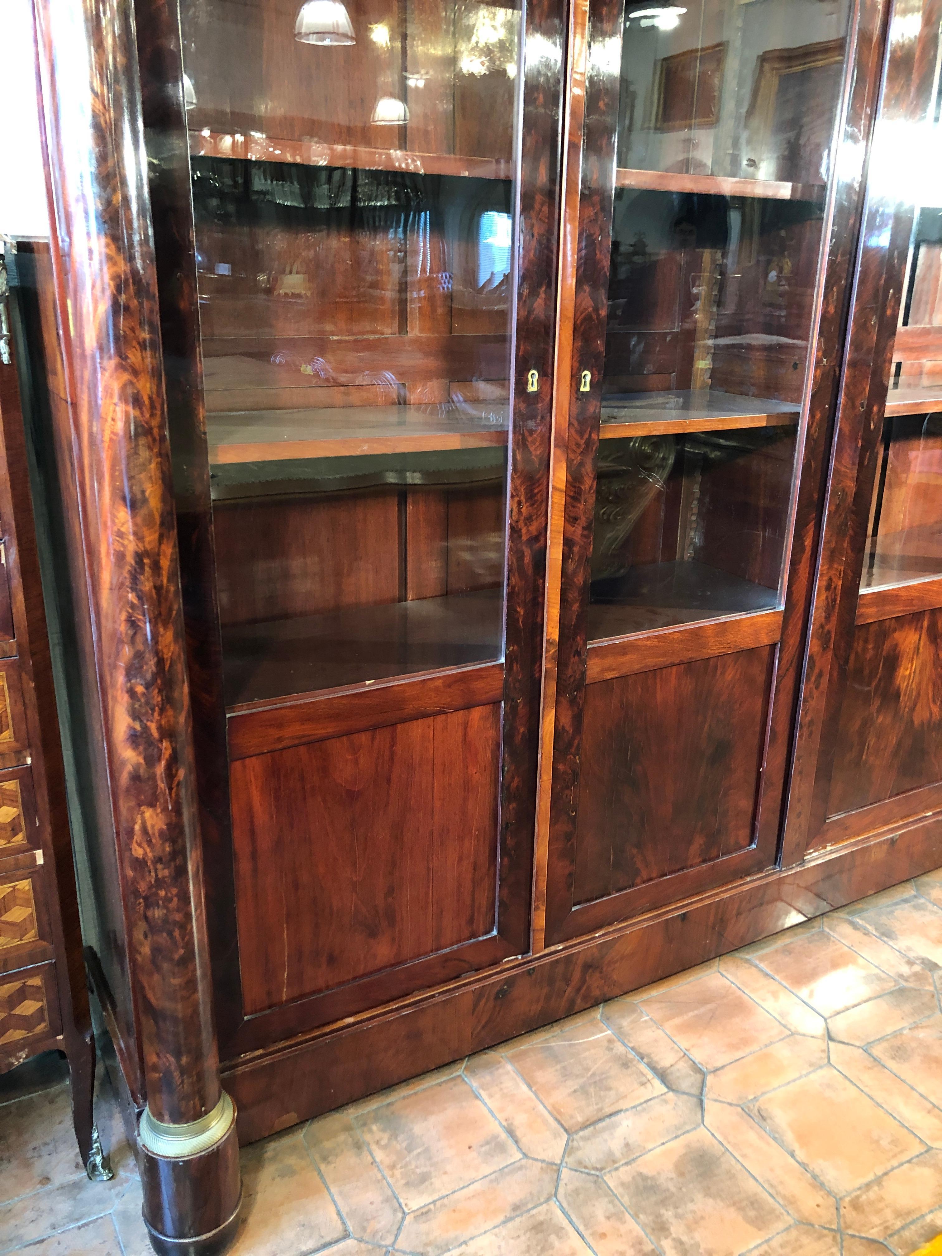Beautiful French bookcase, from the Empire era, in mahogany wood and mahogany feather, with ornaments and applications in gilded bronze and ceased. Four doors, original key. In good state of conservation, small deficiencies and imperfections. To be