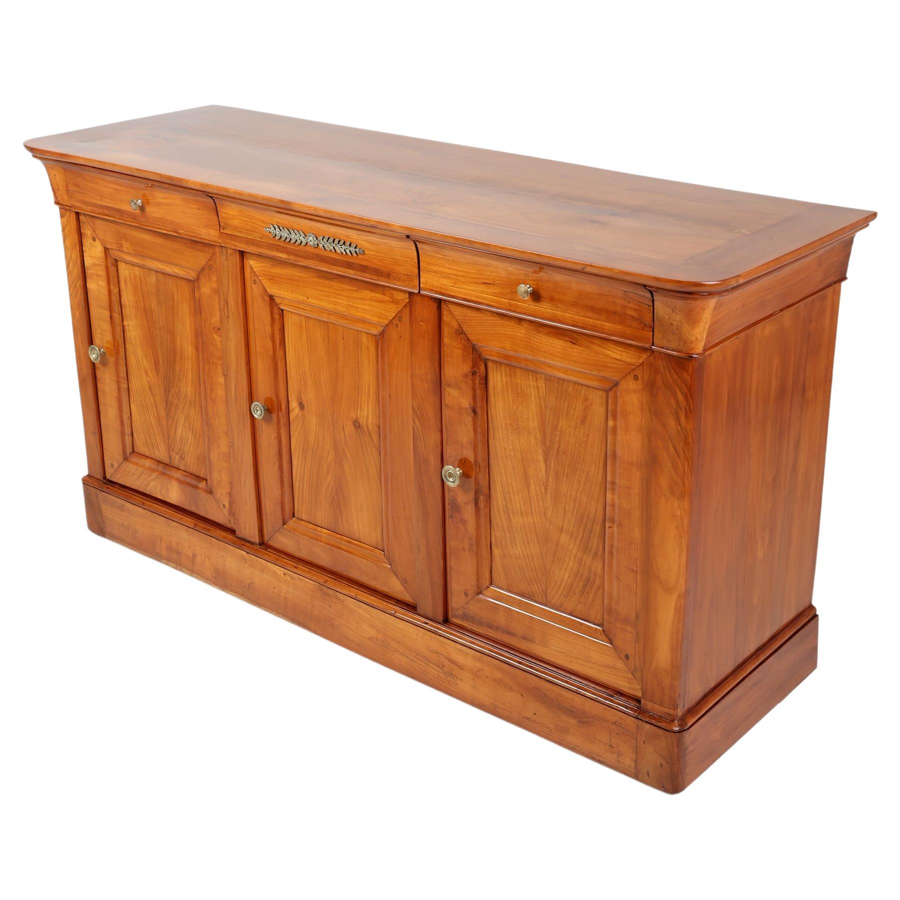 Buffet ou buffet d'époque Empire du 19e siècle
France, 1830
Bois de cerisier,

Ce buffet français du début du XIXe siècle est construit en merisier massif. Trois tiroirs à queue d'aronde s'insèrent dans le tablier et sont dotés de poignées en bronze
