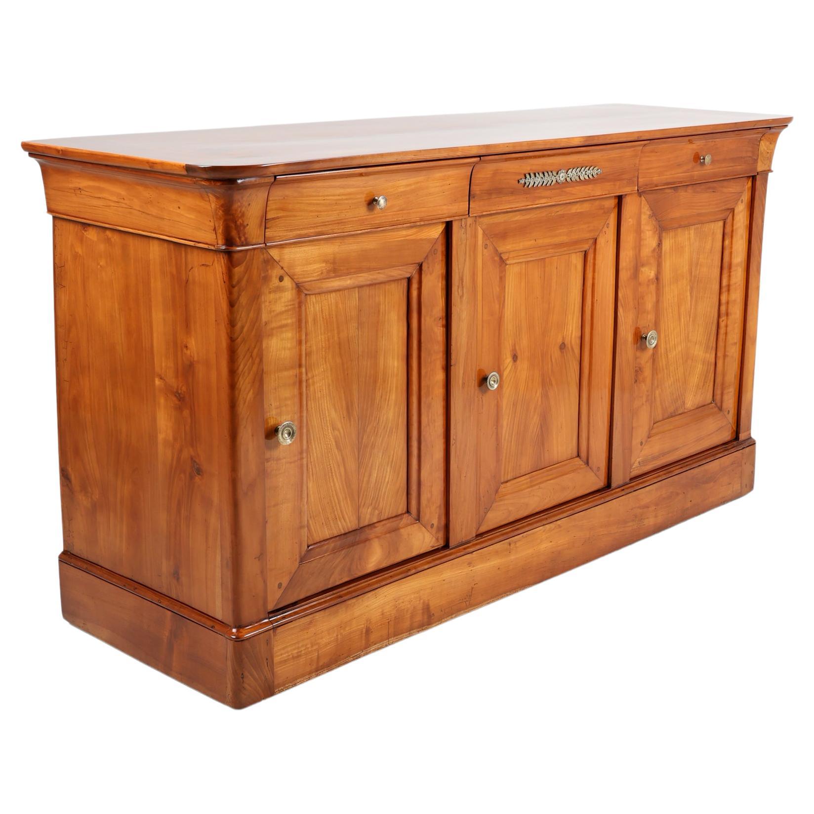 19th Century Empire Period Sideboard or Buffet
France, 1830
Cherrywood,

This early nineteenth century French Buffet is constructed of solid Cherrywood. Three drawers of dovetail construction fit into the apron and are appointed with bronze drawer