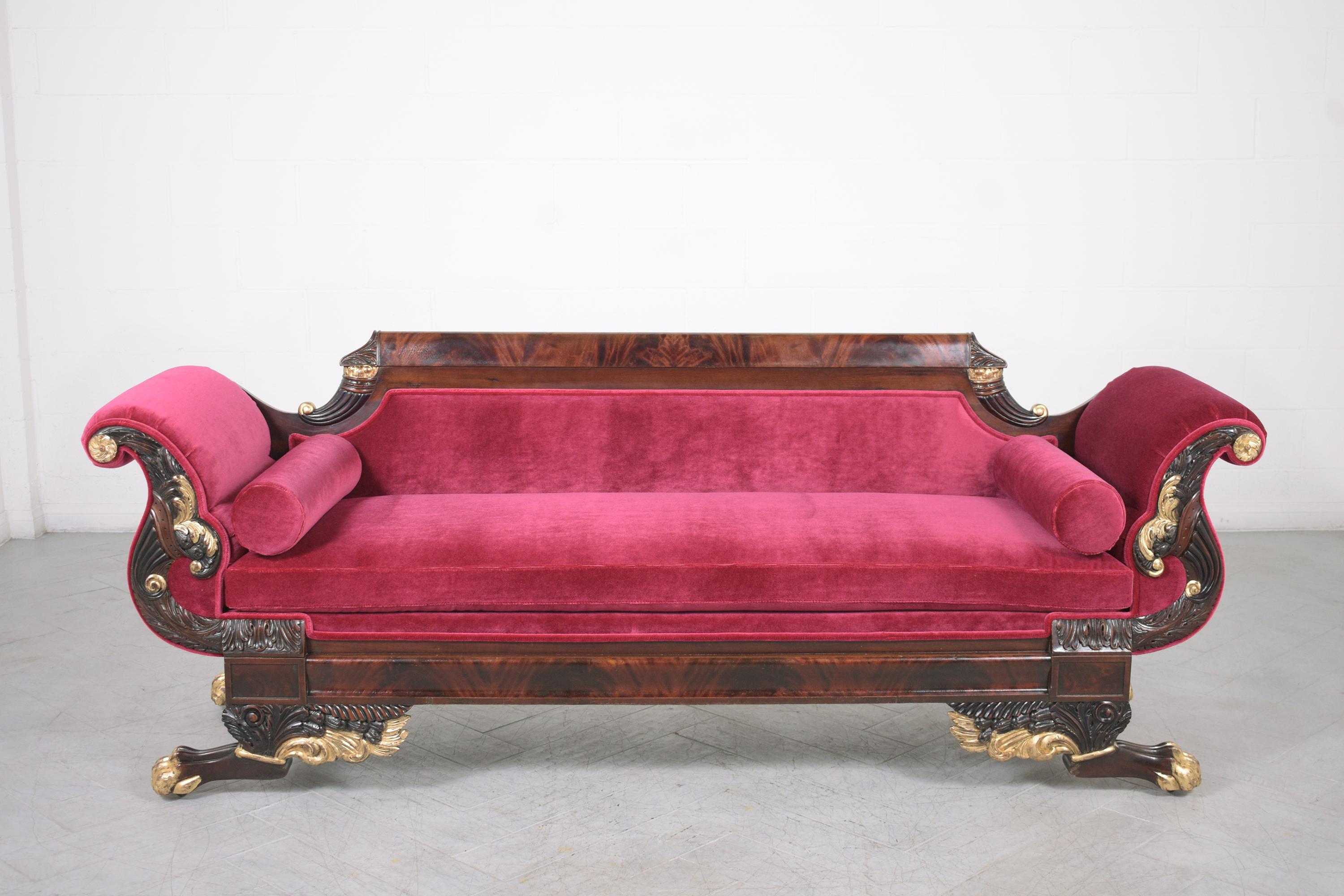 An extraordinary antique empire sofa handcrafted out of mahogany wood and is in great condition fully restored by our professional craftsman team. This elegant sofa is eye-catching and features exquisite carved details throughout the back, scroll