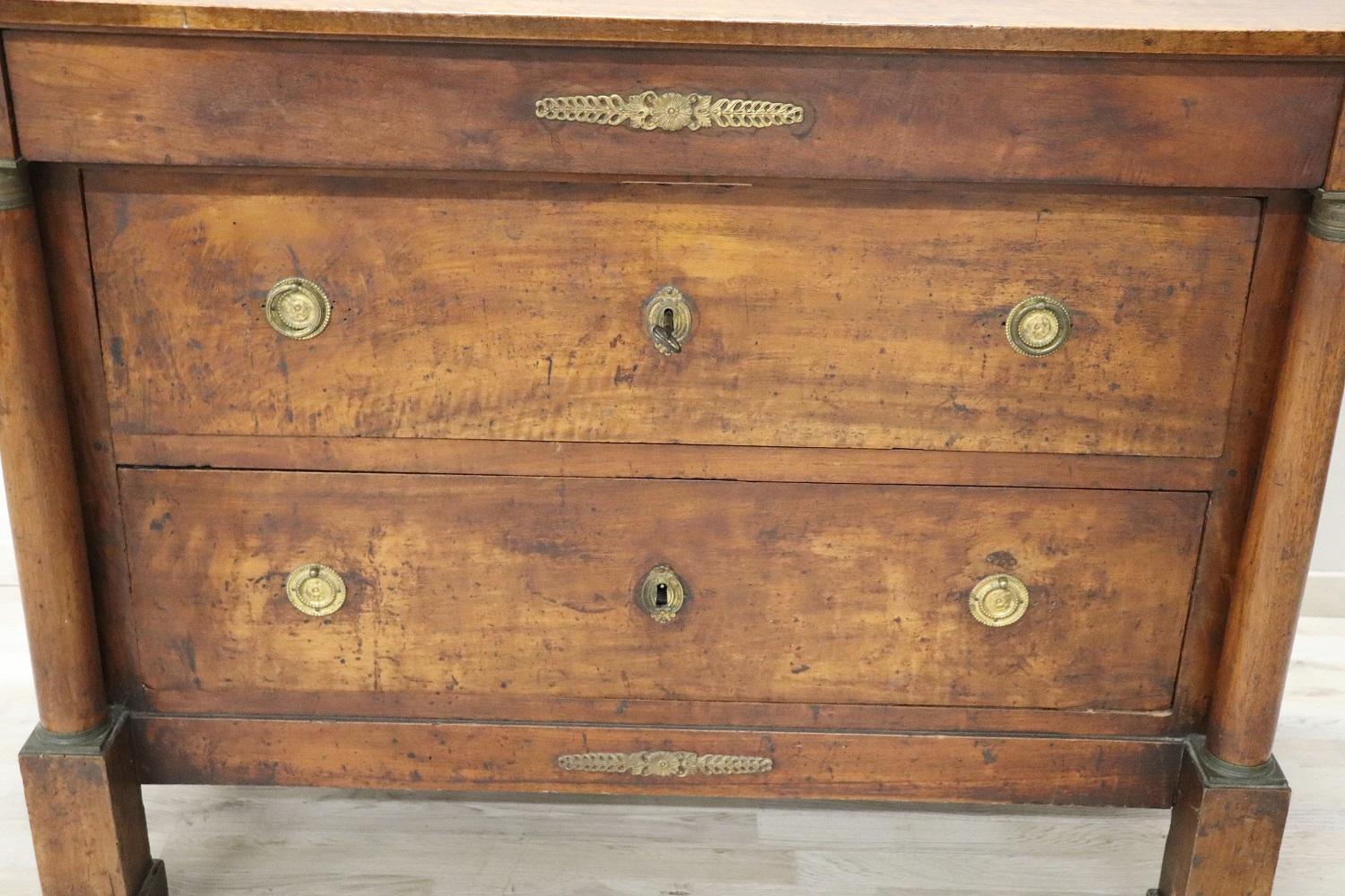 Important antique Italian chest of drawers 1800s in solid walnut wood. The commode is very refined linear and elegant. On the front two large decorative columns. Precious decorations in finely chiselled gilded bronze. Equipped with three comfortable