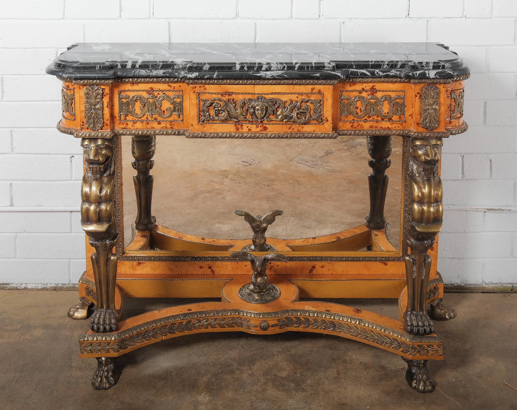Extraordinaire table console néoclassique du XIXe siècle de style néo-empire, avec des supports monopodes en bronze doré, des feuilles d'acanthe et un riche cadre en placage de ronce d'amboine. Le plateau en marbre noir frappant avec des veines