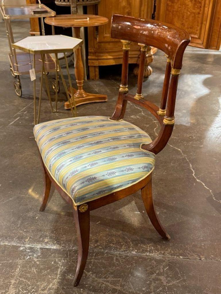 The 19th Century Empire Style Mahogany and Gilt Side Chair is a luxurious and elegant piece of furniture perfect for adults in a mid-century modern home decor setting. Made of high-quality mahogany with a lavish gilt finish, this chair exudes