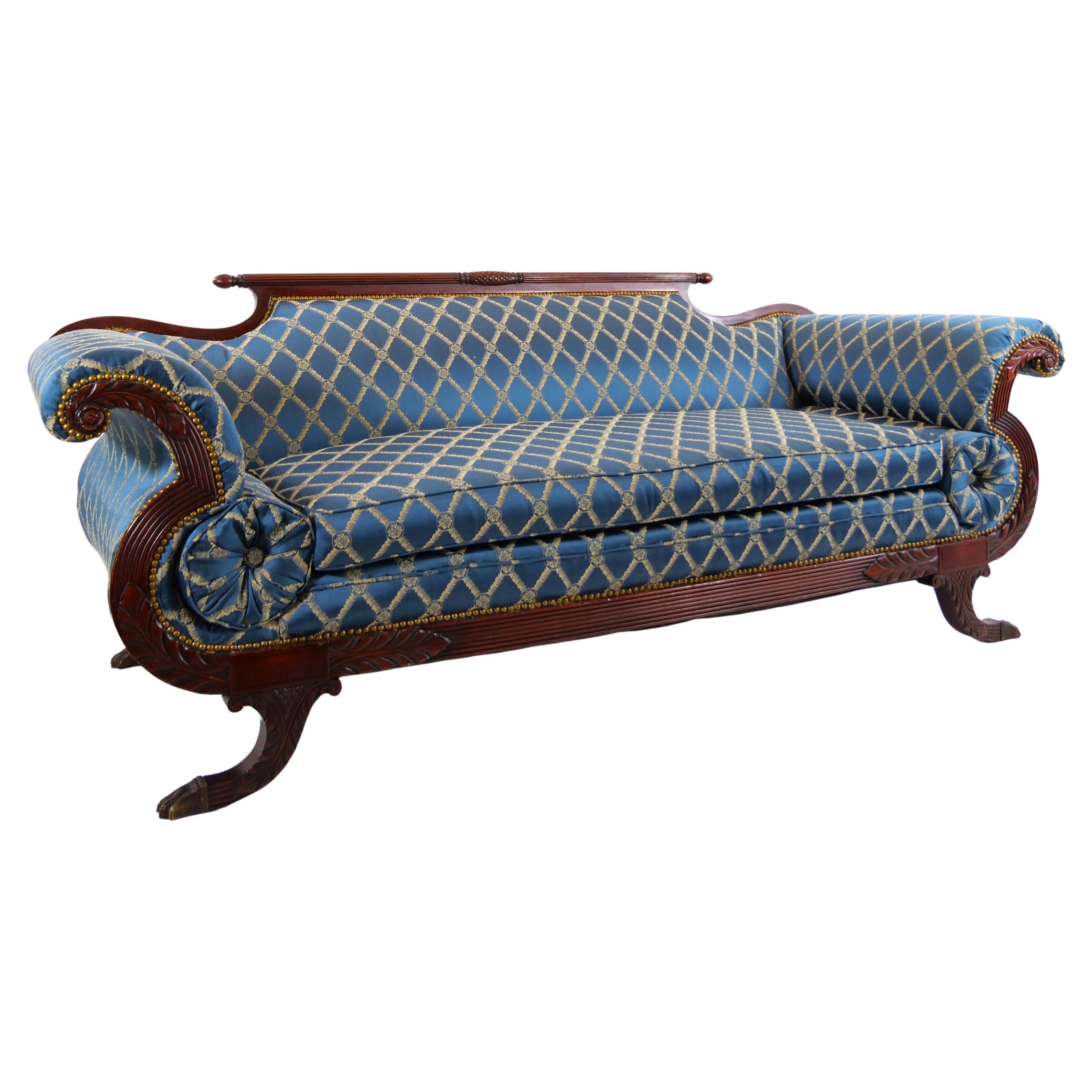 Very beautiful North American Empire style mahogany wood framed upholstered sofa with matching bolster pillows and mahogany frame scrolled arms and lions paw feet. The sofa is in great condition, just beautiful and roomy. The upholstery is very