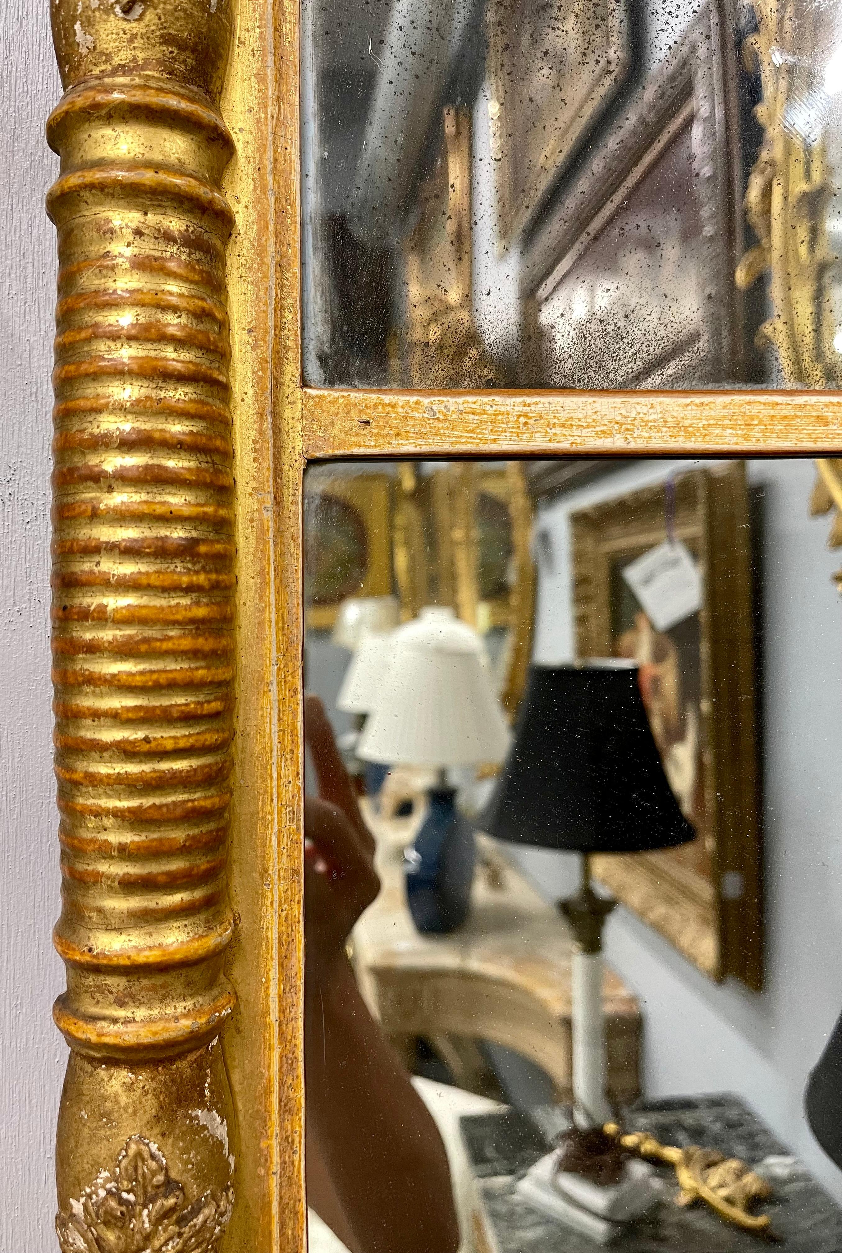 wand- oder Tischspiegel im Empire-Stil des 19. Jahrhunderts. Der zweiteilige Spiegel hat einen vergoldeten Rahmen im Empire-Design mit vollständig geschnitzten Stützen, die in einem geformten Oberteil mit einem unteren kreisförmigen Kugeldesign