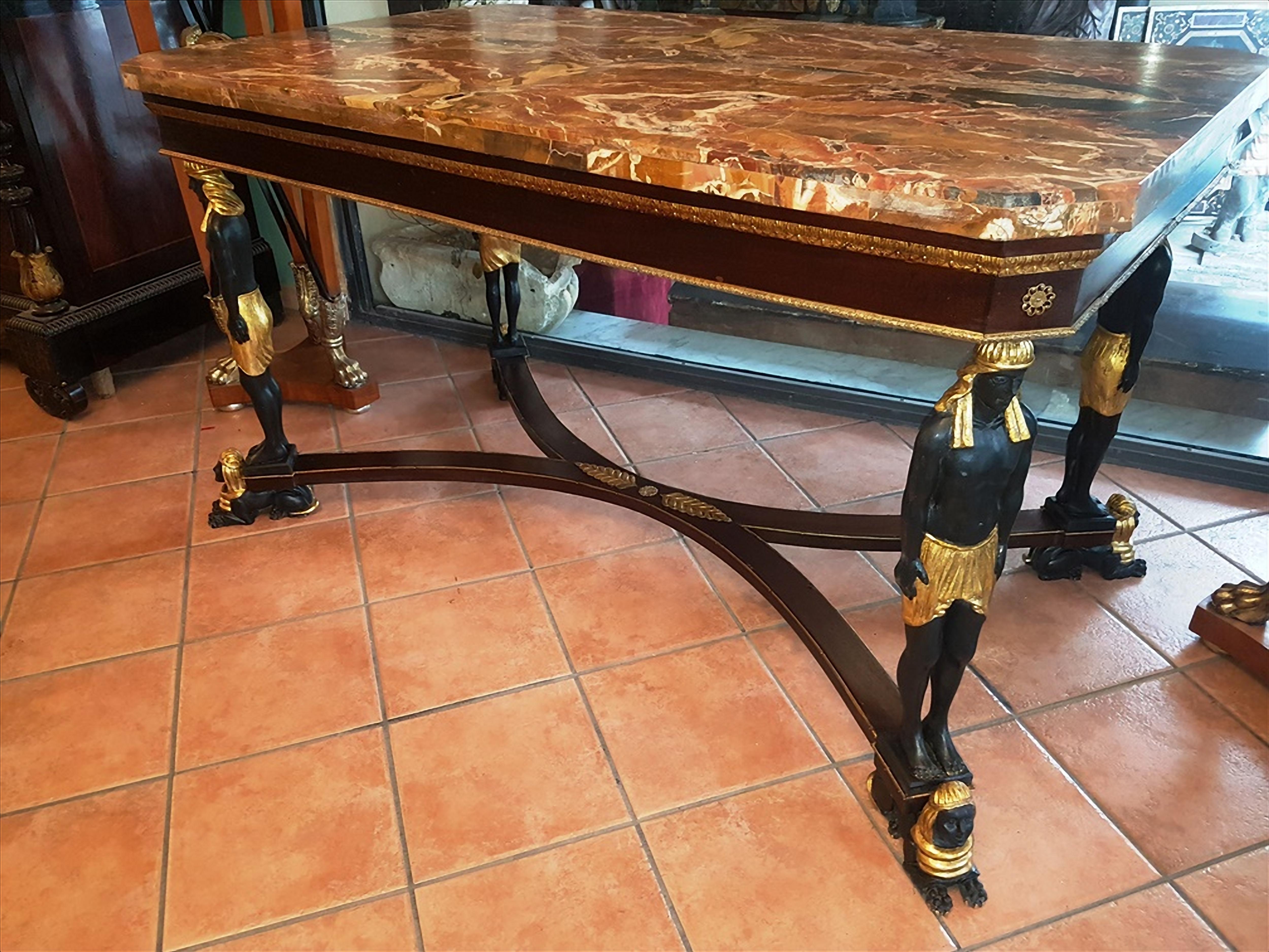 Important table veneered in mahogany, with applications in gilded bronze. Note the caryatids that support the upper floor, in carved and gilded ebony. Feet in the shape of a sphinx In the lower part.