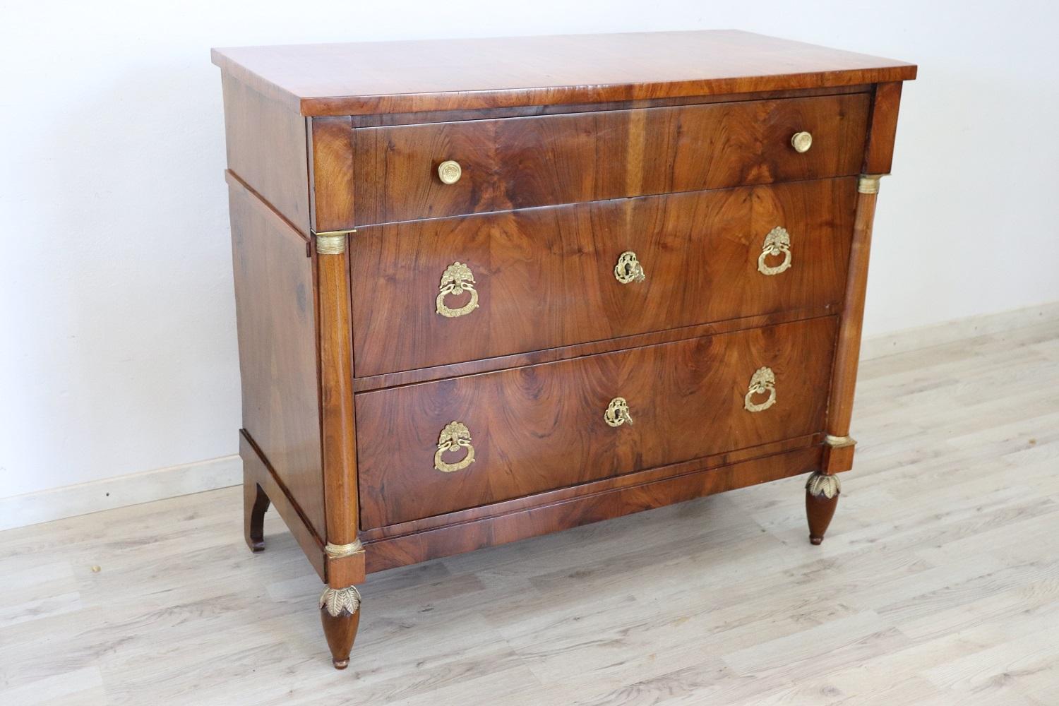 Important antique Italian chest of drawers 1800s in walnut wood. The commode is very refined linear and elegant. On the front three large drawers with two columns at the sides enriched with gilded capitals. Rich finely chiseled gilded bronzes. Very