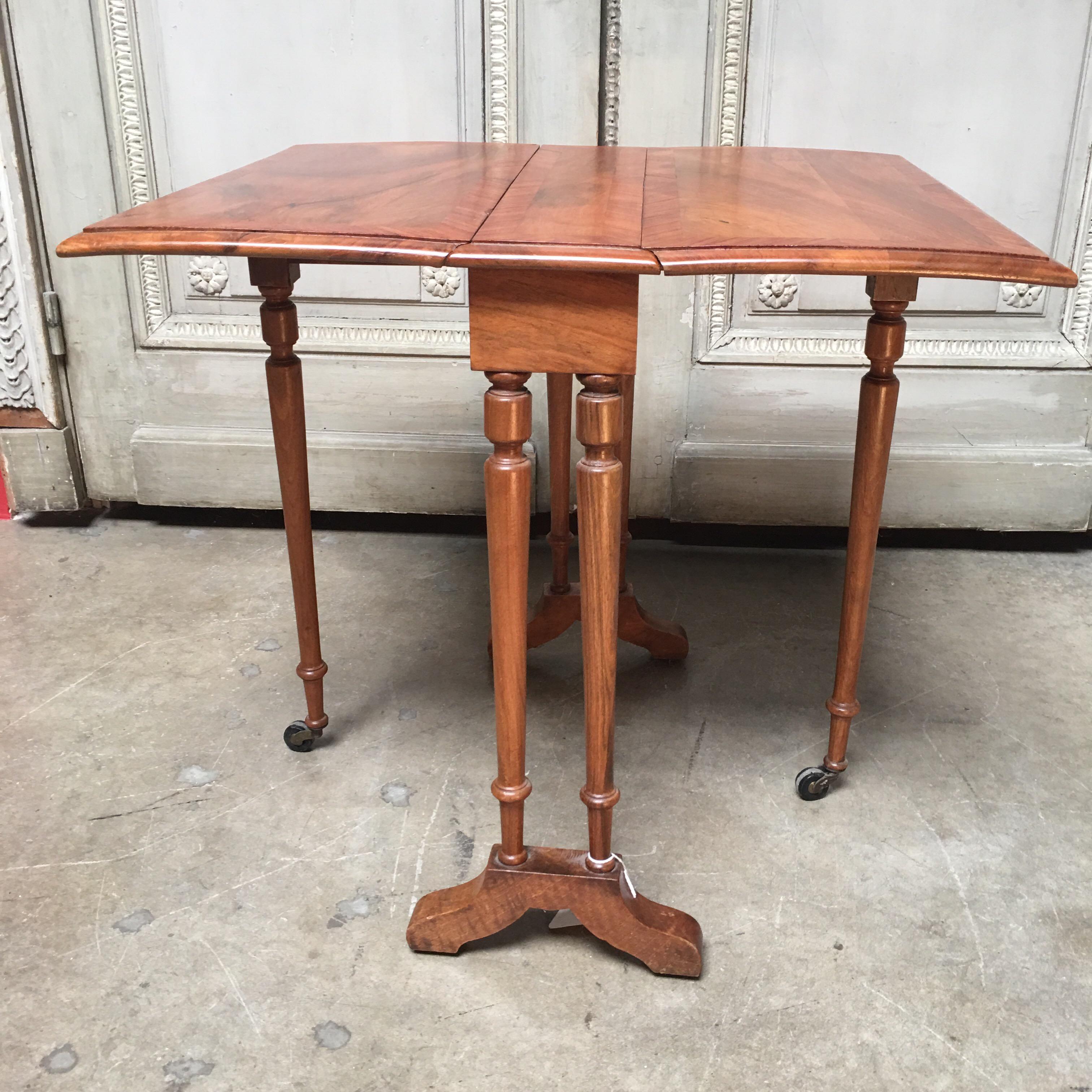 A small scale 19th century English Sutherland table with lovely walnut and kingwood veneer, two drop leaves, supported by turned shaped column ends, turned swing out leg, original castors


