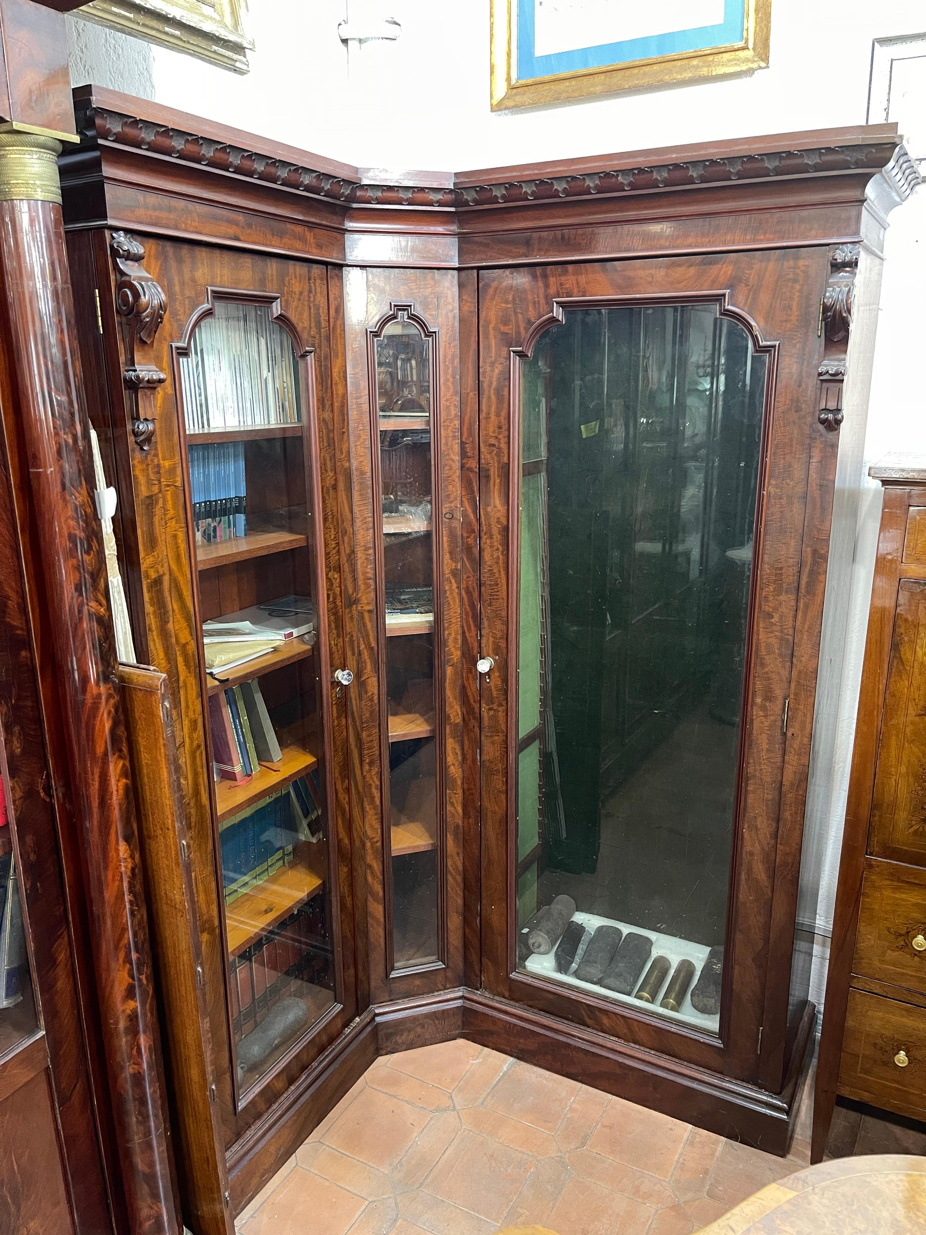 Rare English study cabinet, corner bookcase, with two doors and a small fixed door, in mahogany wood of great quality and with a beautiful grain. Enriched by carved parts. Early Victorian period. On one side fixed shelves, on the other side movable