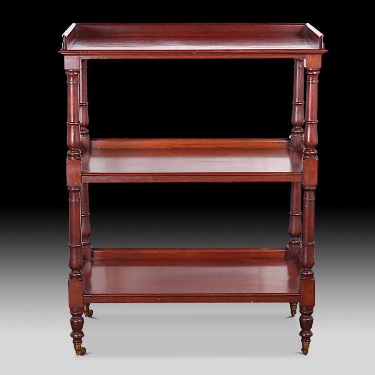 A mid-Victorian solid mahogany 3-tier server or dumbwaiter with turned column supports and raised on the original brass castors, the three shelves with three-quarter gallery edge.
C. 1850 – 1860.