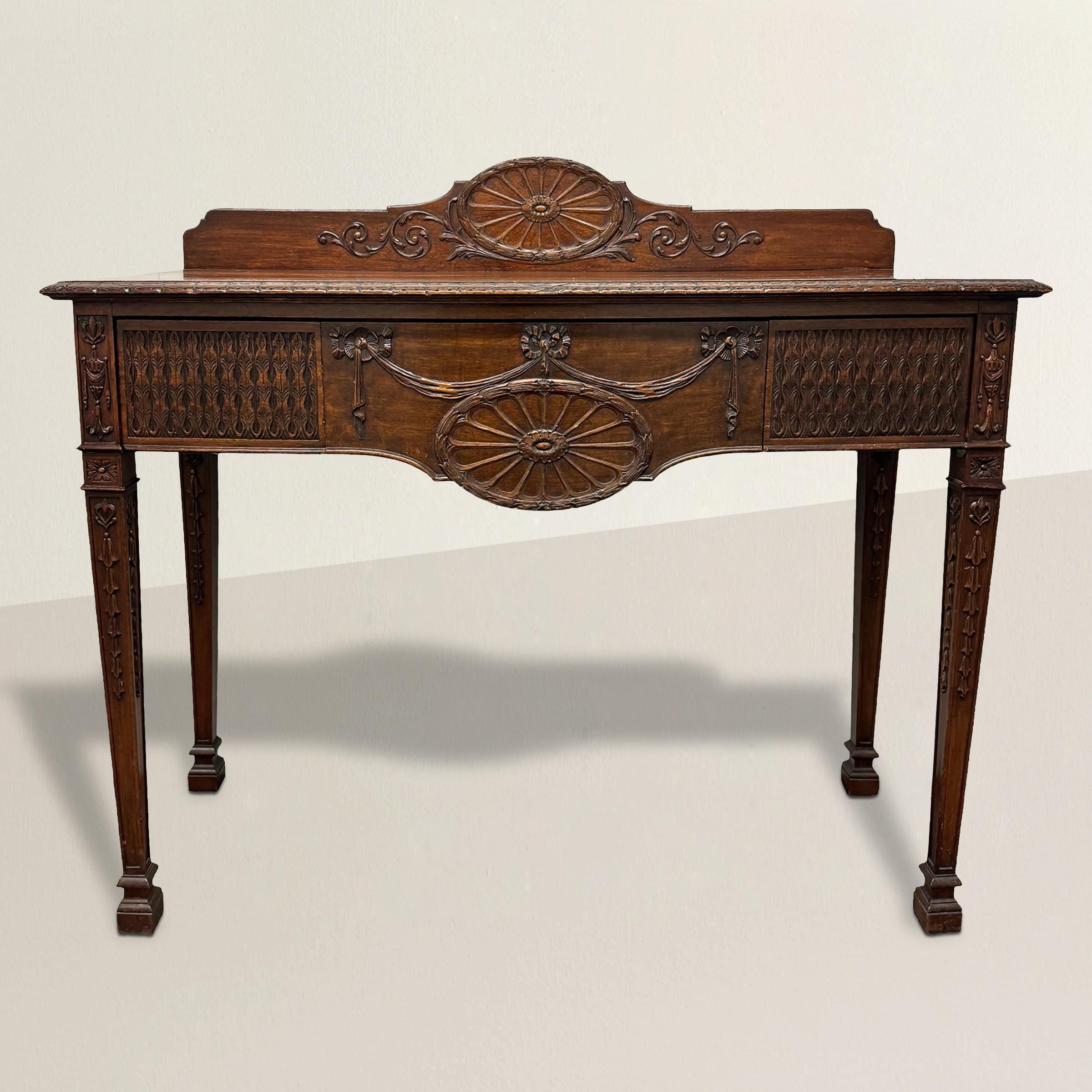 Crafted in the refined tradition of the Adam style, this 19th-century English mahogany console exudes timeless elegance and classical sophistication. The back crest rail is adorned with a grand laurel wreath medallion, a hallmark of Neoclassical