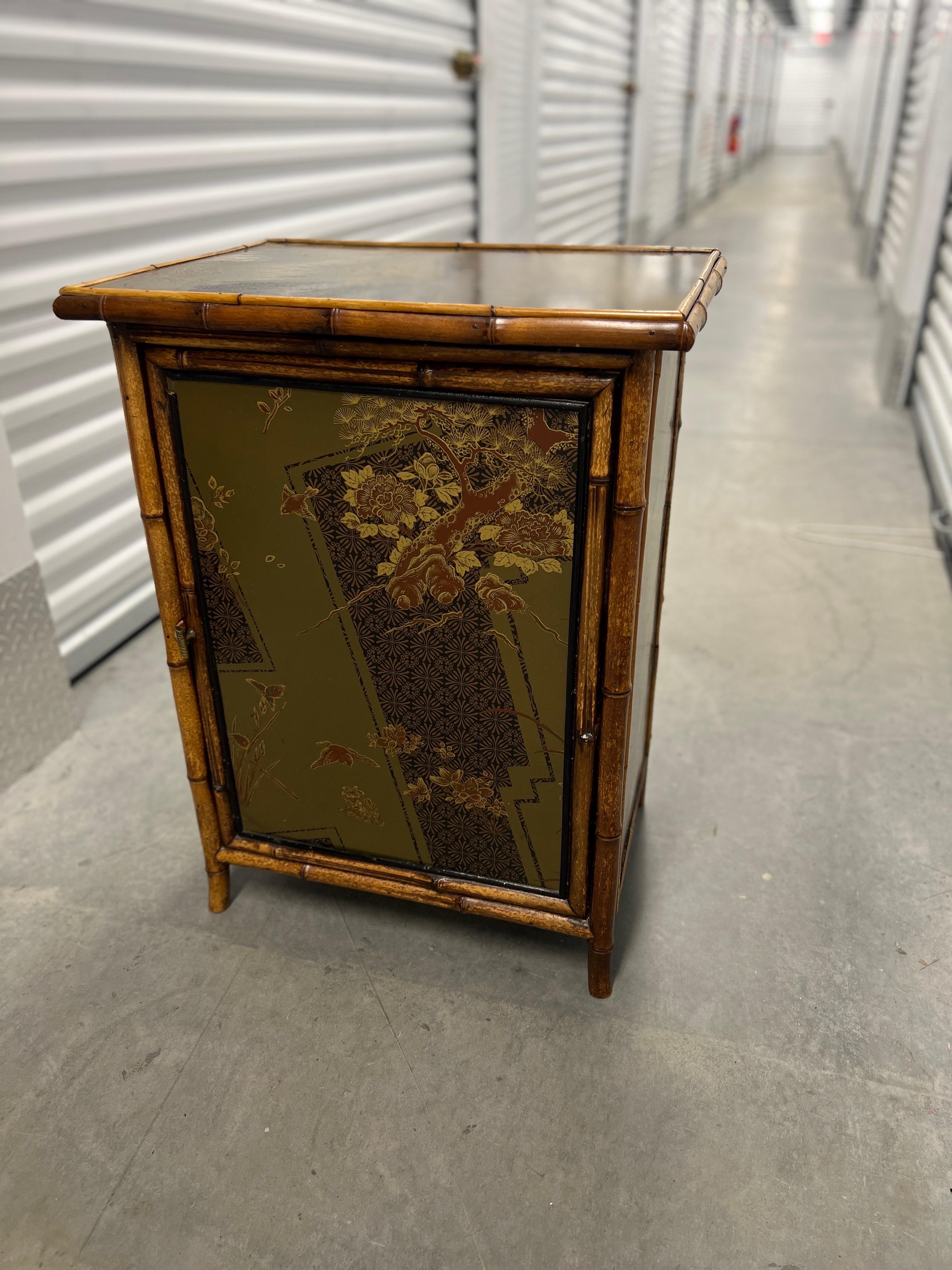 Aesthetic Movement Japanned bamboo cabinet, 19th/20th c., England, the scorched bamboo frame inset with lacquered side panels and doors decorated with birds and flowers in the Japanese chinoiserie taste, doors opening to fixed shelves, the interior