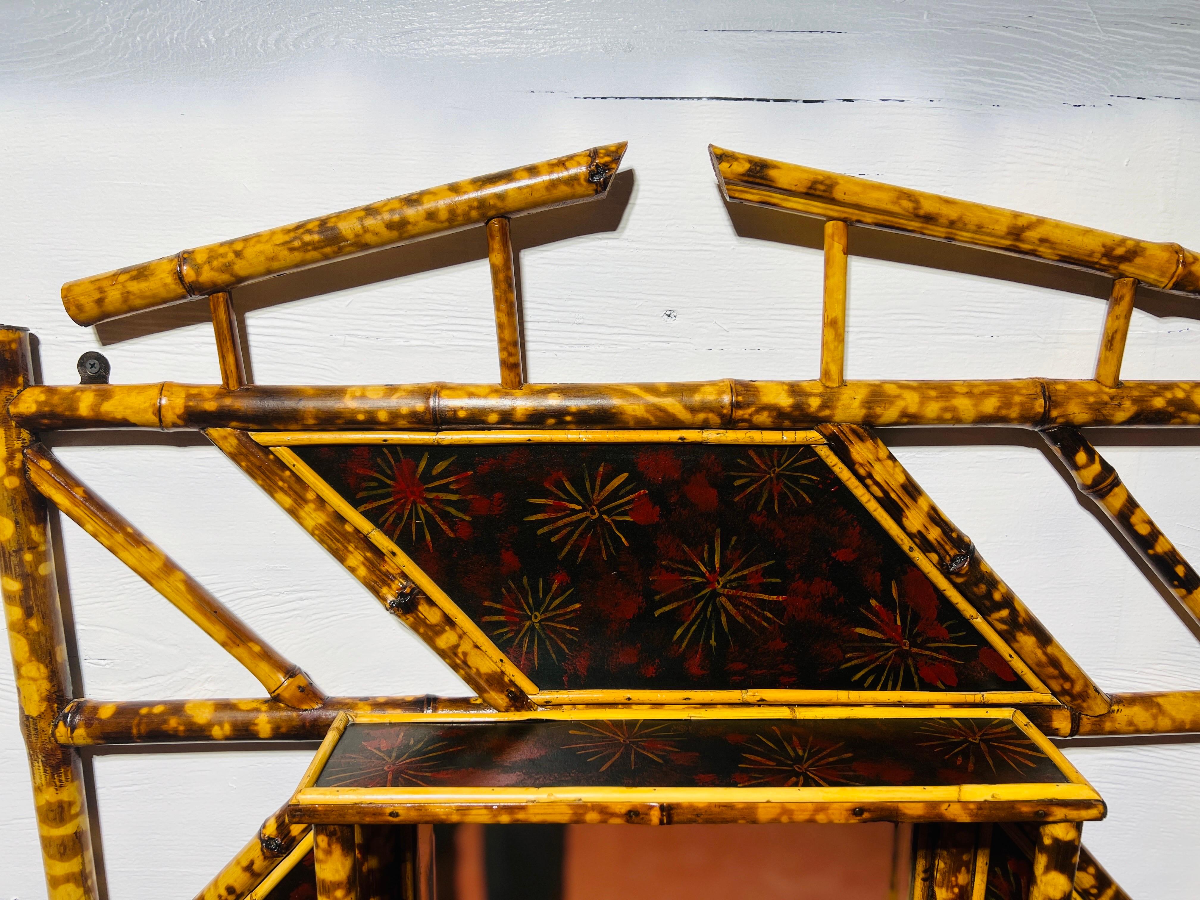 English, late 19th century. A fantastic 19th century Victorian era bamboo wall mirror decorated with chinoiserie lacquer detailing and three sturdy shelves. The bamboo frame is sturdy with a 