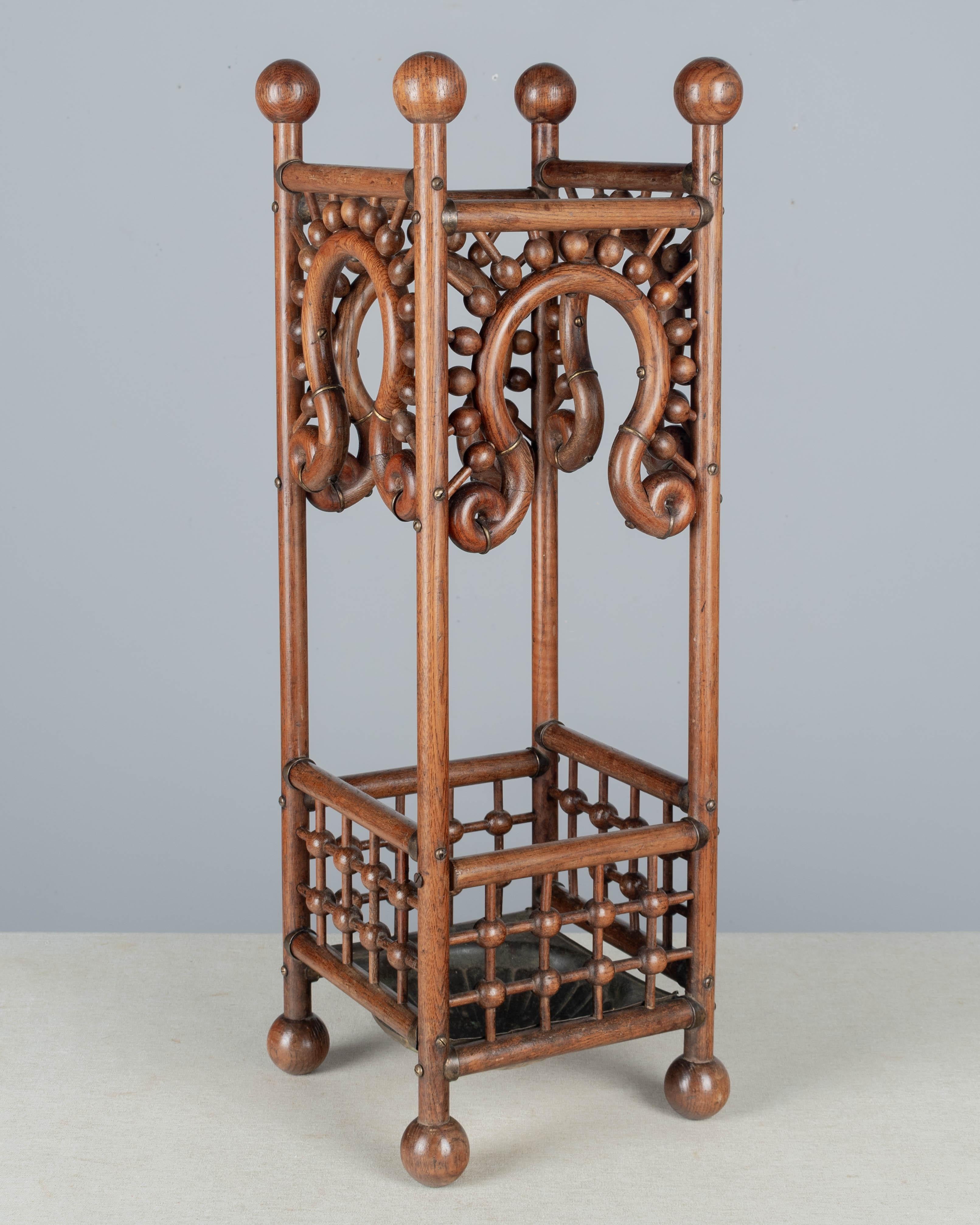 Porte-parapluie ou bâton de marche du mouvement esthétique anglais du XIXe siècle. Fabriqué en chêne avec un motif décoratif en forme de bâton et de boule. Corps en bois carré avec garniture en bois courbé et arrondi et accents en laiton. Plateau en