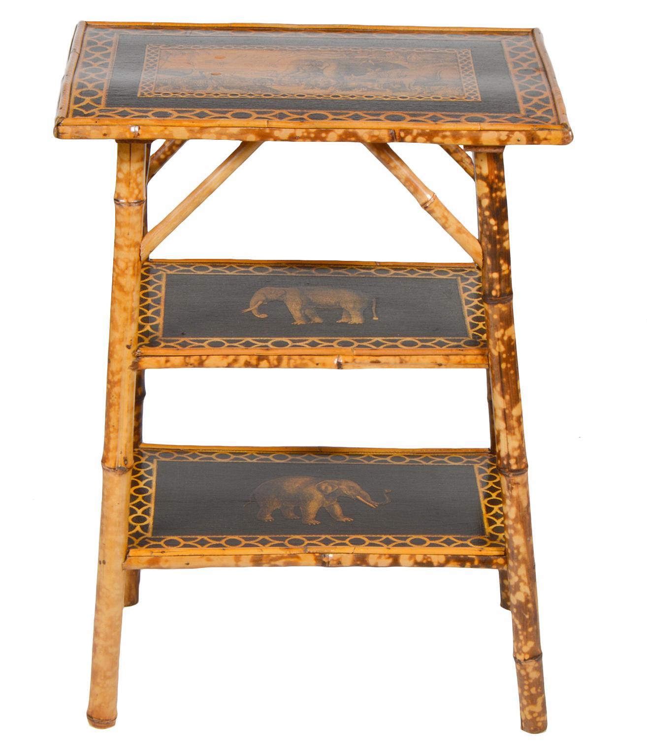 This decorative antique bamboo table features tortoise finish bamboo legs and framework. The top and shelves has later decoupage decoration, the top featuring a Noah's Ark style gathering of wild animals, the two shelves featuring single African