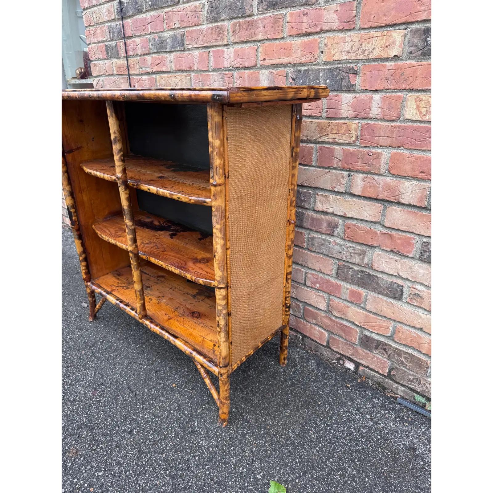 Una antigua librería inglesa de bambú, de vibrantes colores. El respaldo de madera y la parte superior de ratán son bonitos juntos y están en buen estado. Esta pieza es muy estable y robusta para su edad. El contraste de color de este artículo es