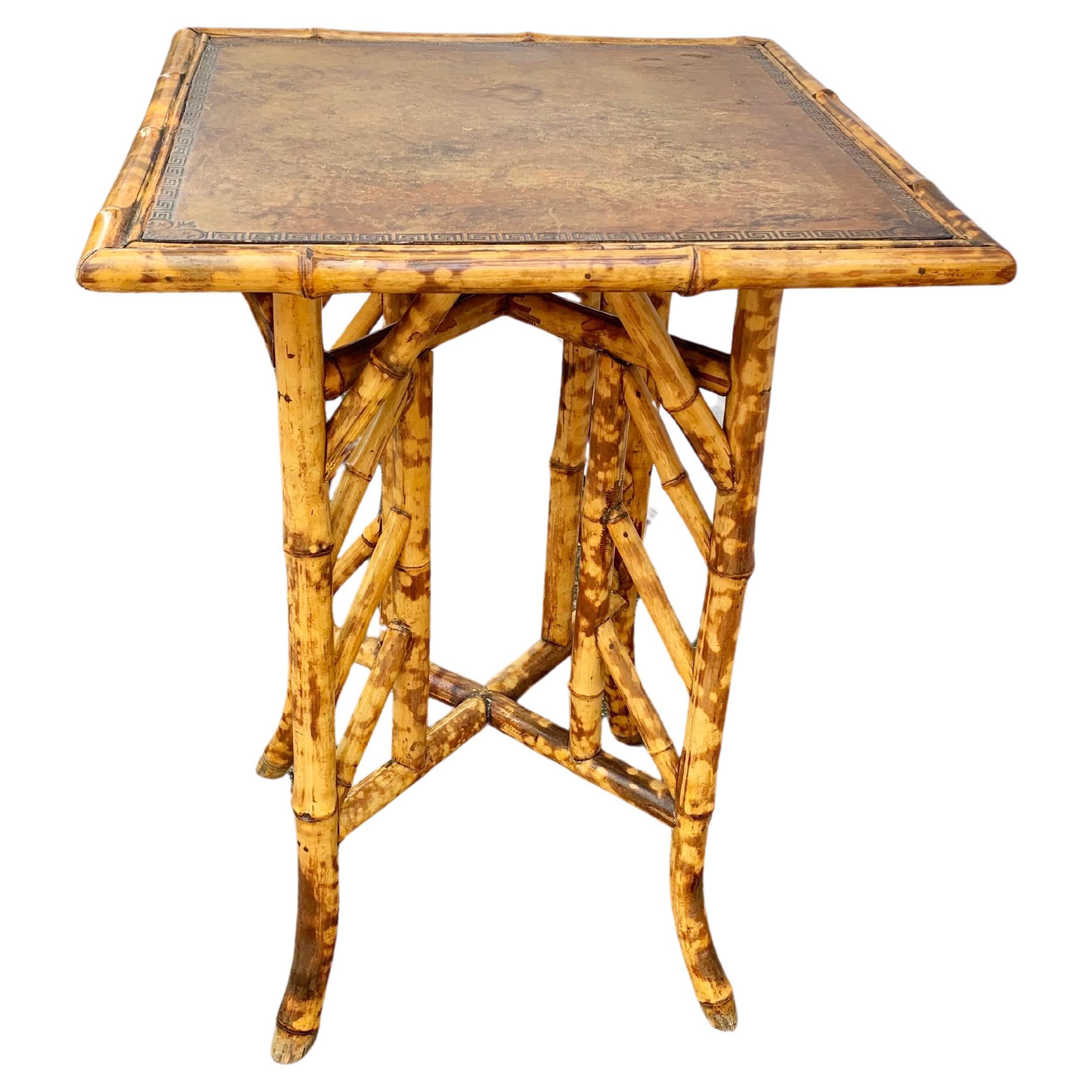 This 19th Century English aesthetic movement occasional or side table was handcrafted in the late 1800's from thick bamboo. The table features a square embossed brown leather top resting on four gently splayed legs that have been conjoined with