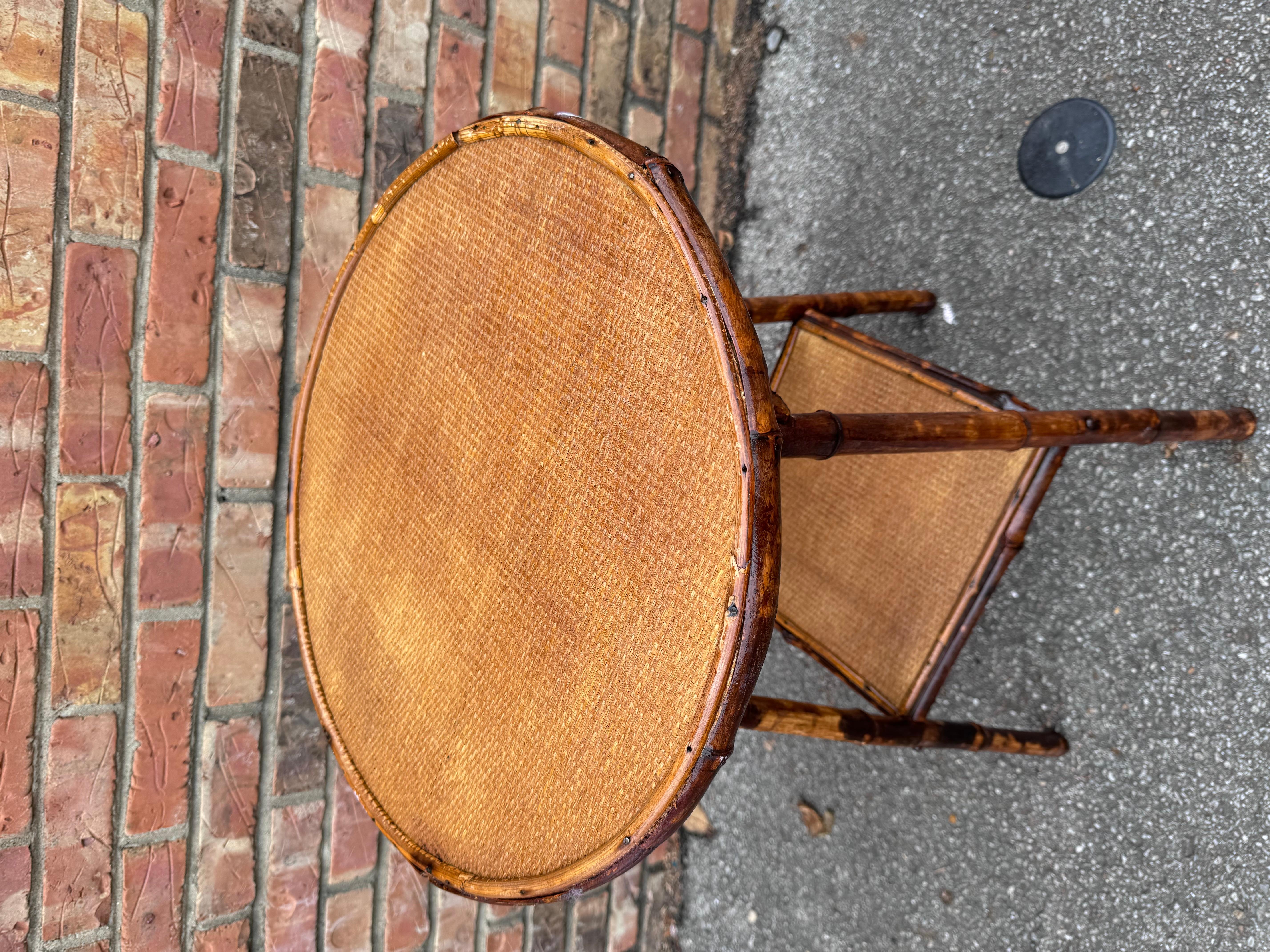 This is a beautiful 19th century English bamboo side table! Tables like these make excellent accent pieces because their color and style is so versatile. The dark hues of the burnt bamboo pair perfectly with the lighter golden of the rattan top and