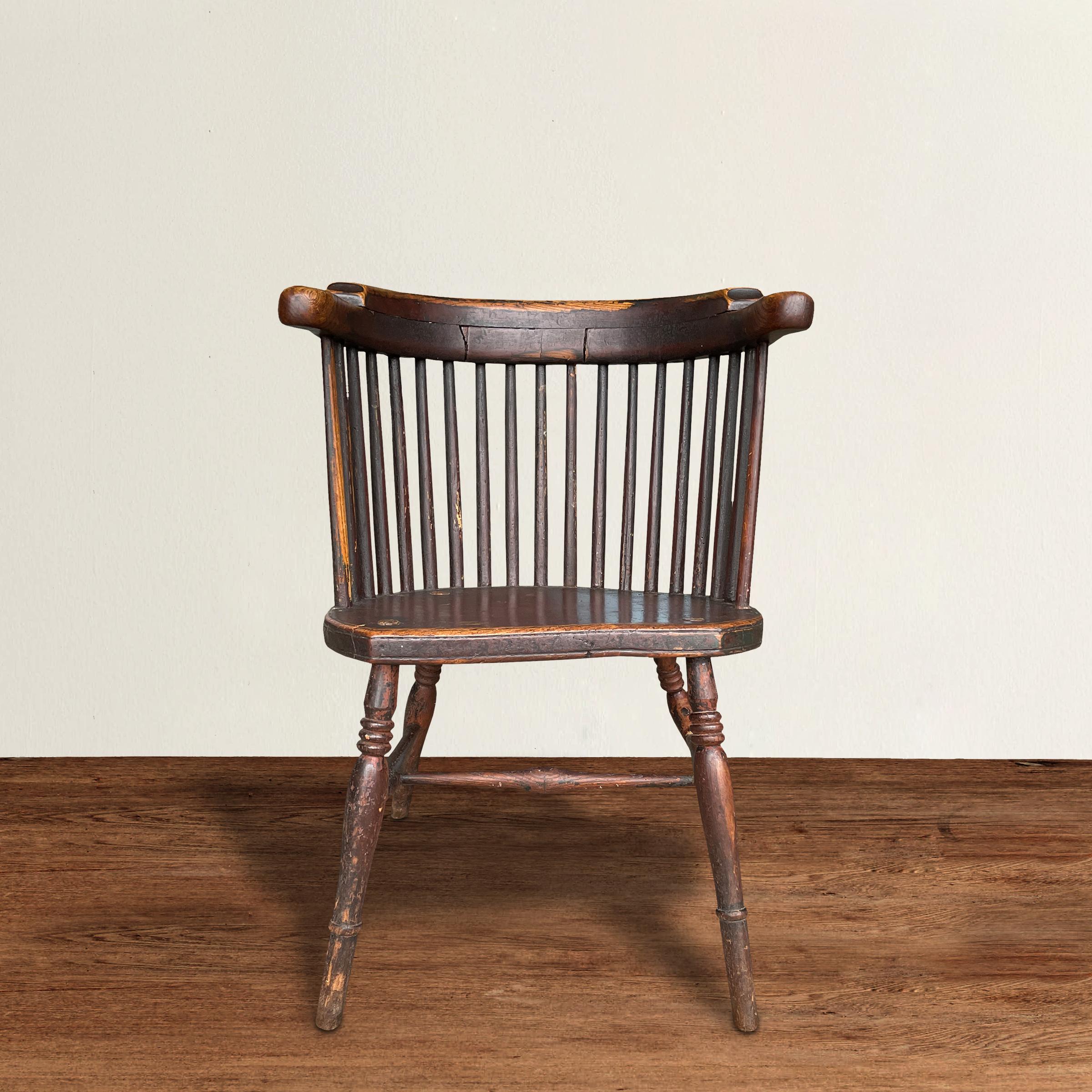 A lovable 19th century English barrelback Windsor arm chair with a graceful rounded crest-rail supported by several spindles, a sturdy saddle seat, splayed turned legs, and retaining its original sangre-de-boeuf painted finish.