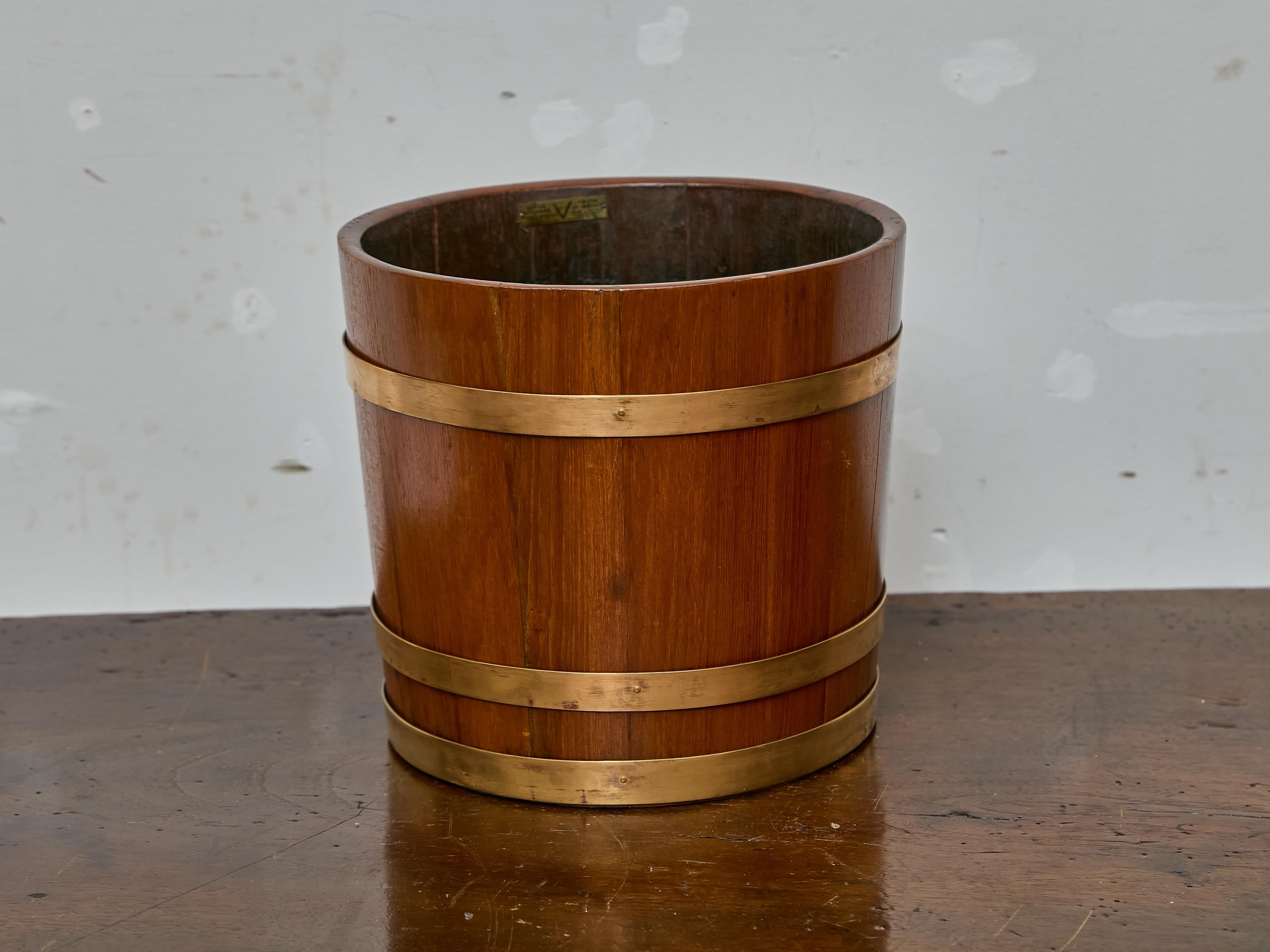 Crafted in England during the 19th century, this handsome oak bucket features a classic rounded silhouette and is reinforced with three solid brass bands. The combination of warm-toned oak and the soft golden sheen of the brass creates a visually