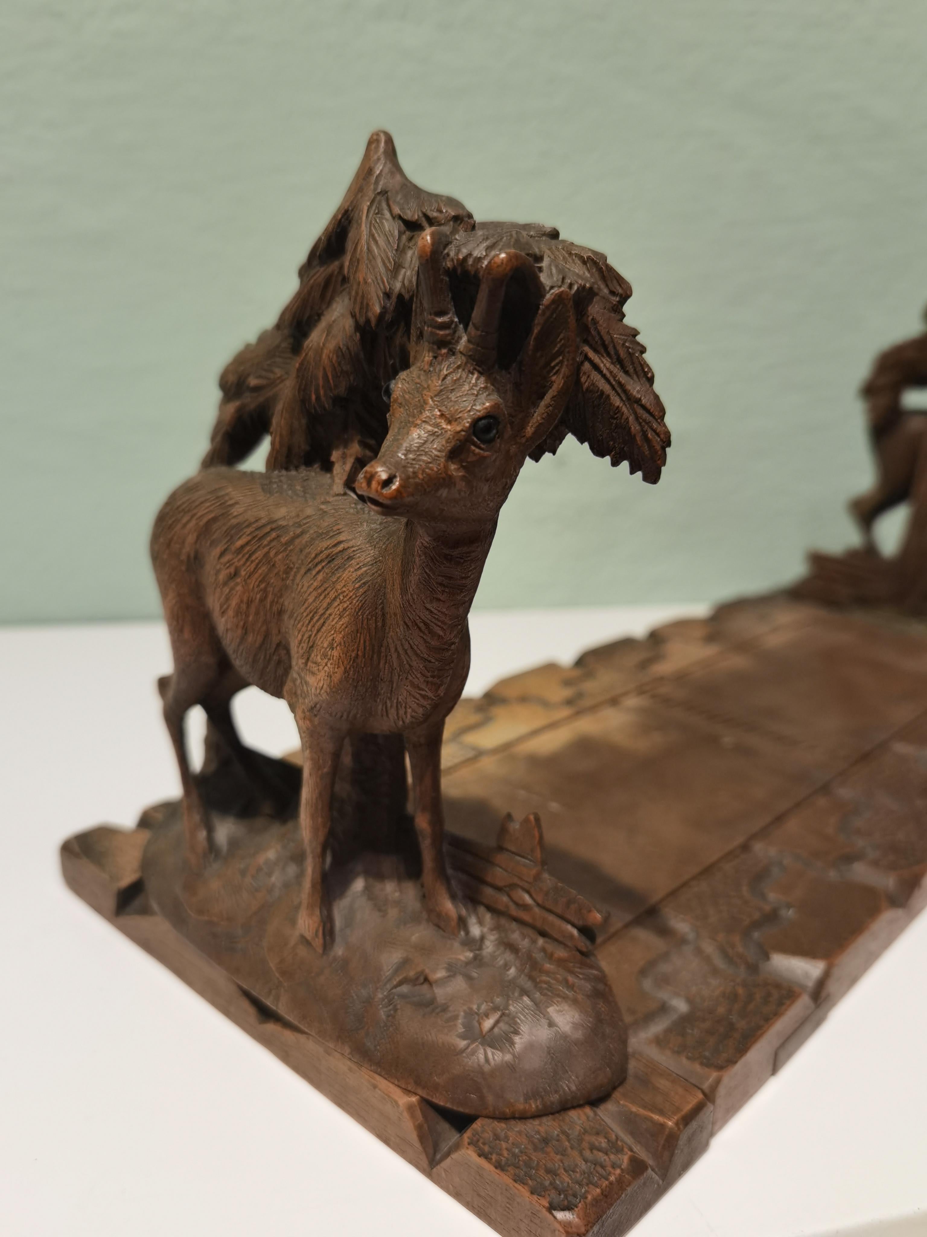 A rare 19th century antique black forest hand carved wooden book slide depicting two deers set to naturalistic tree setting with carved detailed base.