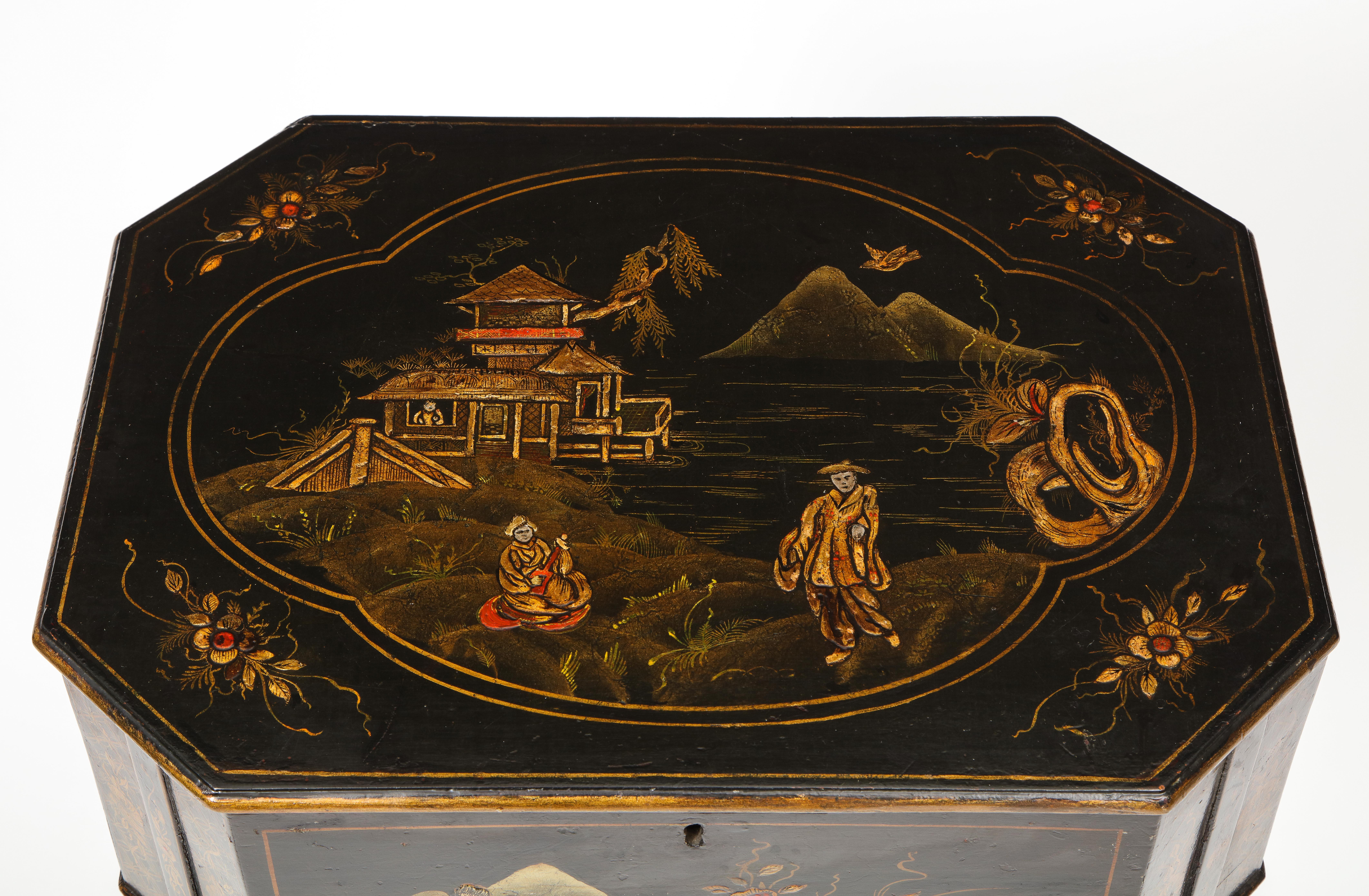 Mit vergoldetem Chinoiserie-Dekor, das Figuren in einer Berglandschaft auf schwarzem Grund zeigt; der rechteckige Deckel mit Scharnier und abgeschrägter Ecke öffnet sich zu einem mit Papier ausgekleideten Innenraum; er steht auf spitz zulaufenden