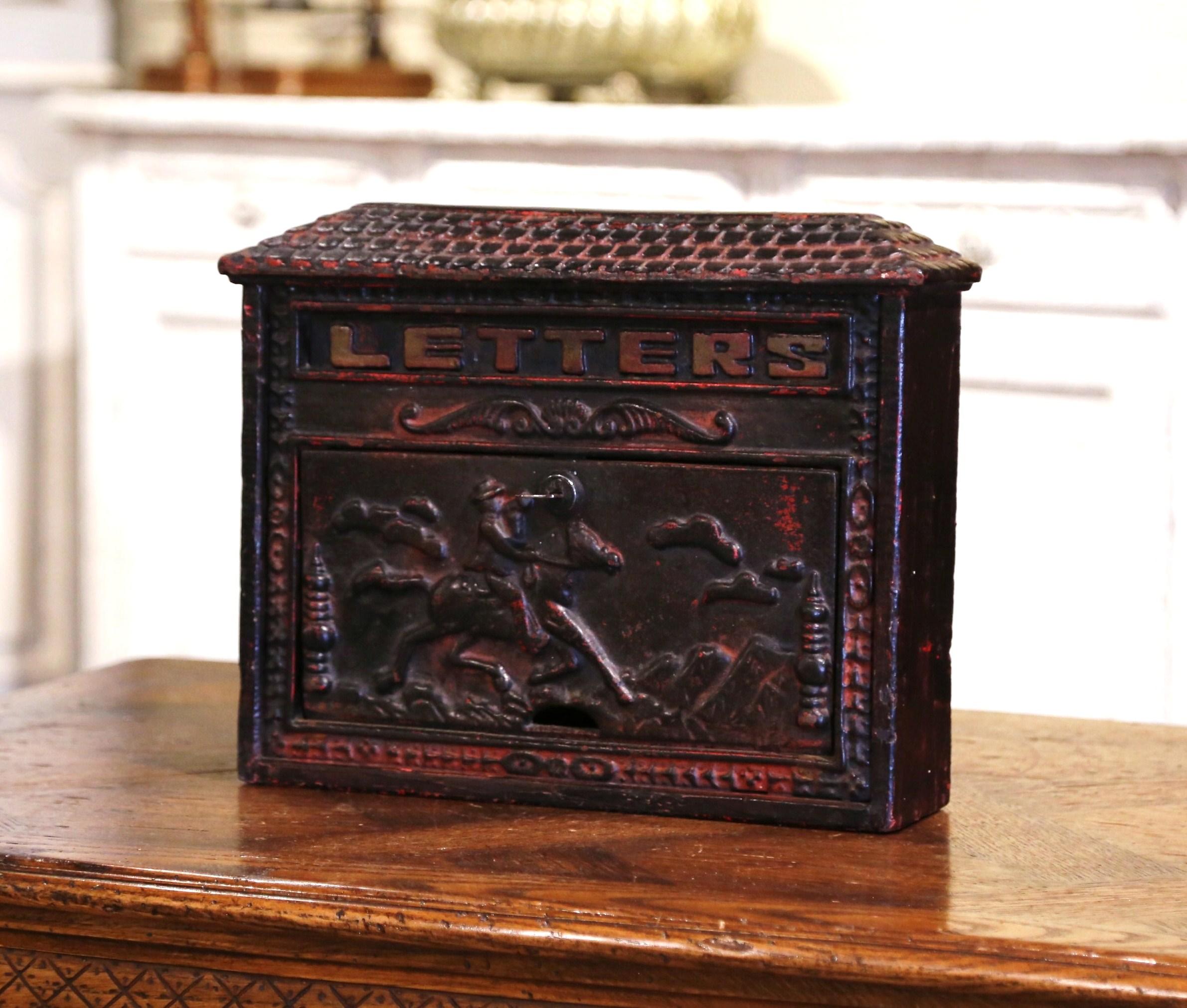 This antique iron mailbox was forged in England, circa 1880. The wall mail holder features high reliefs decorations on the front door including a pastoral scene and a horseman on his mount. The front has a envelope slot with word 
