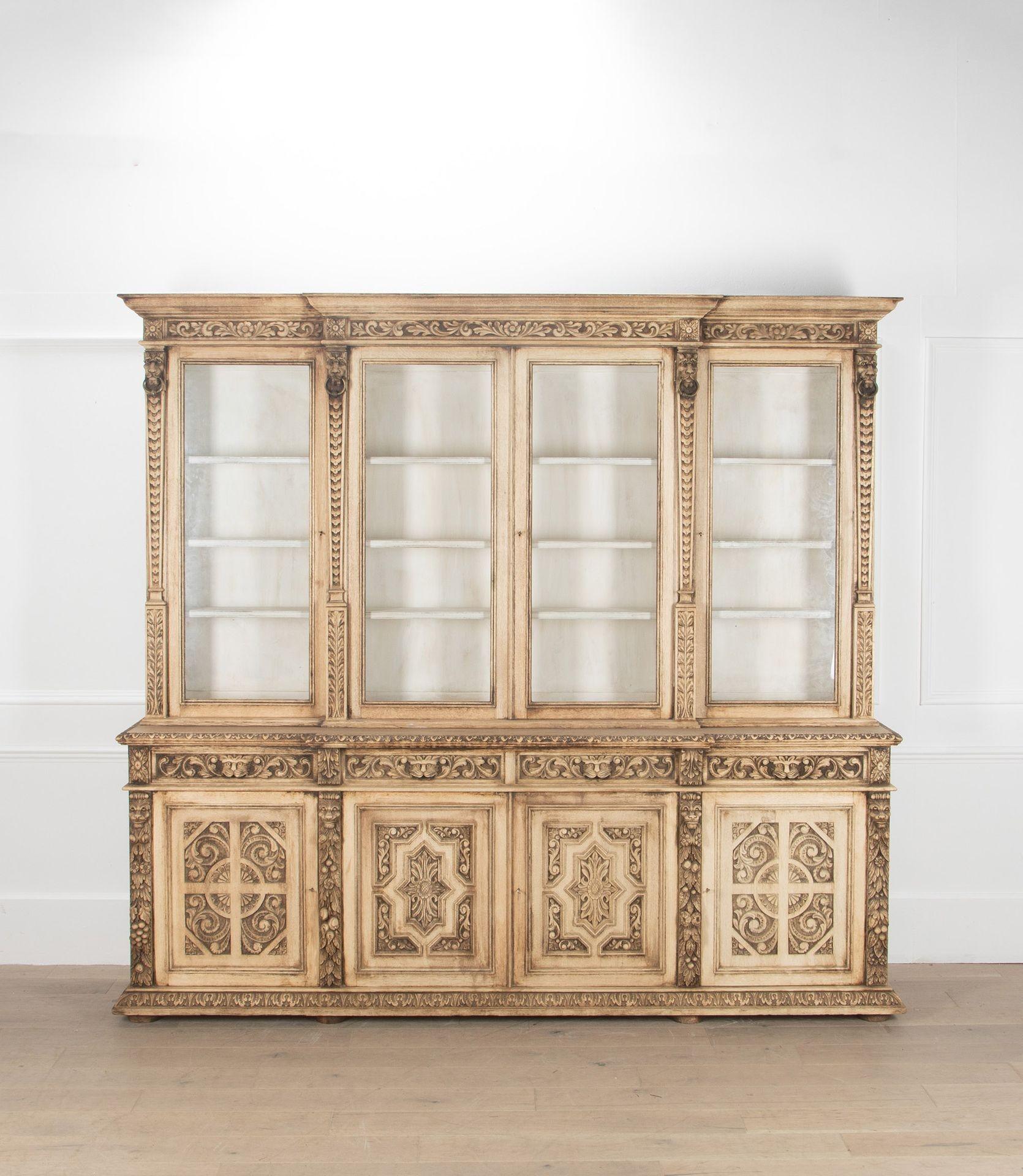 A fantastic and very impressive bleached oak bookcase.
This stunning piece offers fantastic display storage in the glazed top section which is painted in old white paint.
Below there is a hidden storage behind the four carved oak doors and