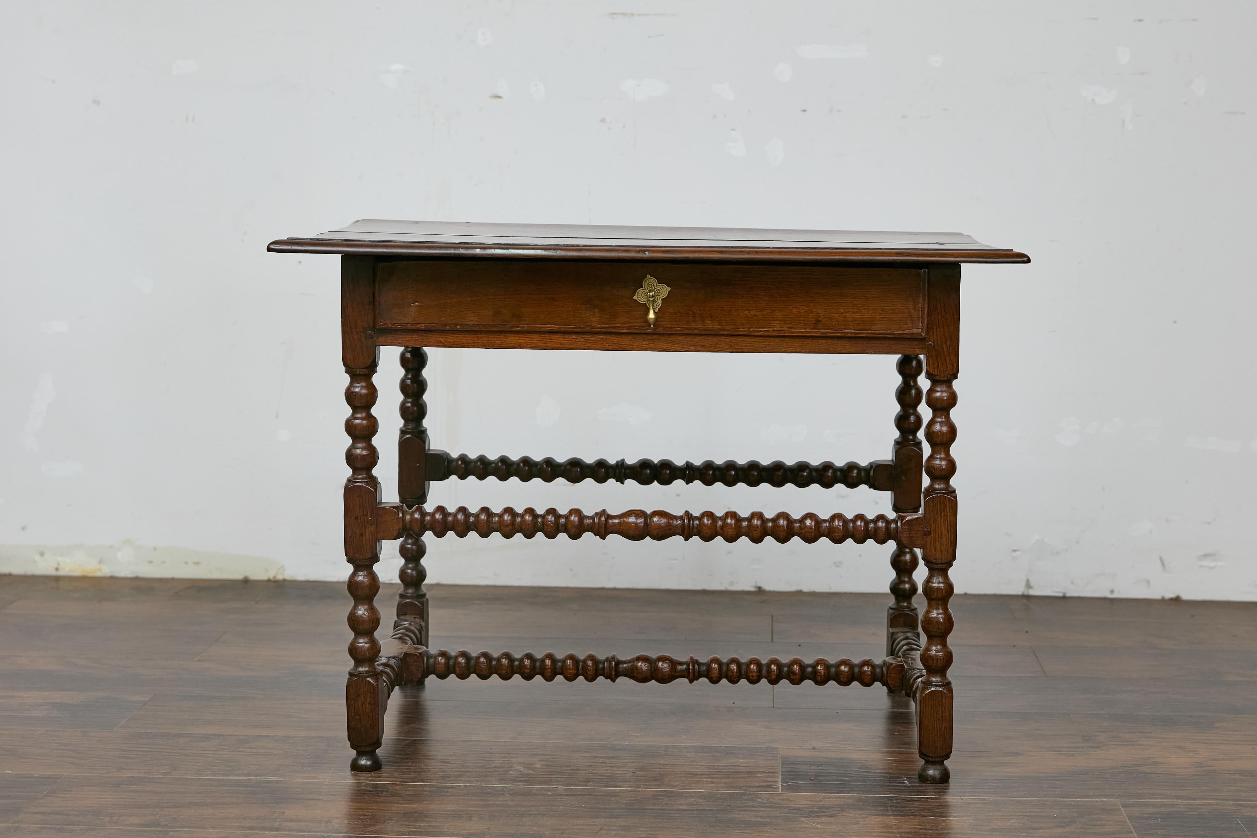Table d'appoint anglaise en chêne du XIXe siècle avec un seul tiroir et une traverse en forme de H. Cette table d'appoint en chêne anglais du XIXe siècle à pieds en fuseaux dégage un charme intemporel grâce à son artisanat raffiné et à son design
