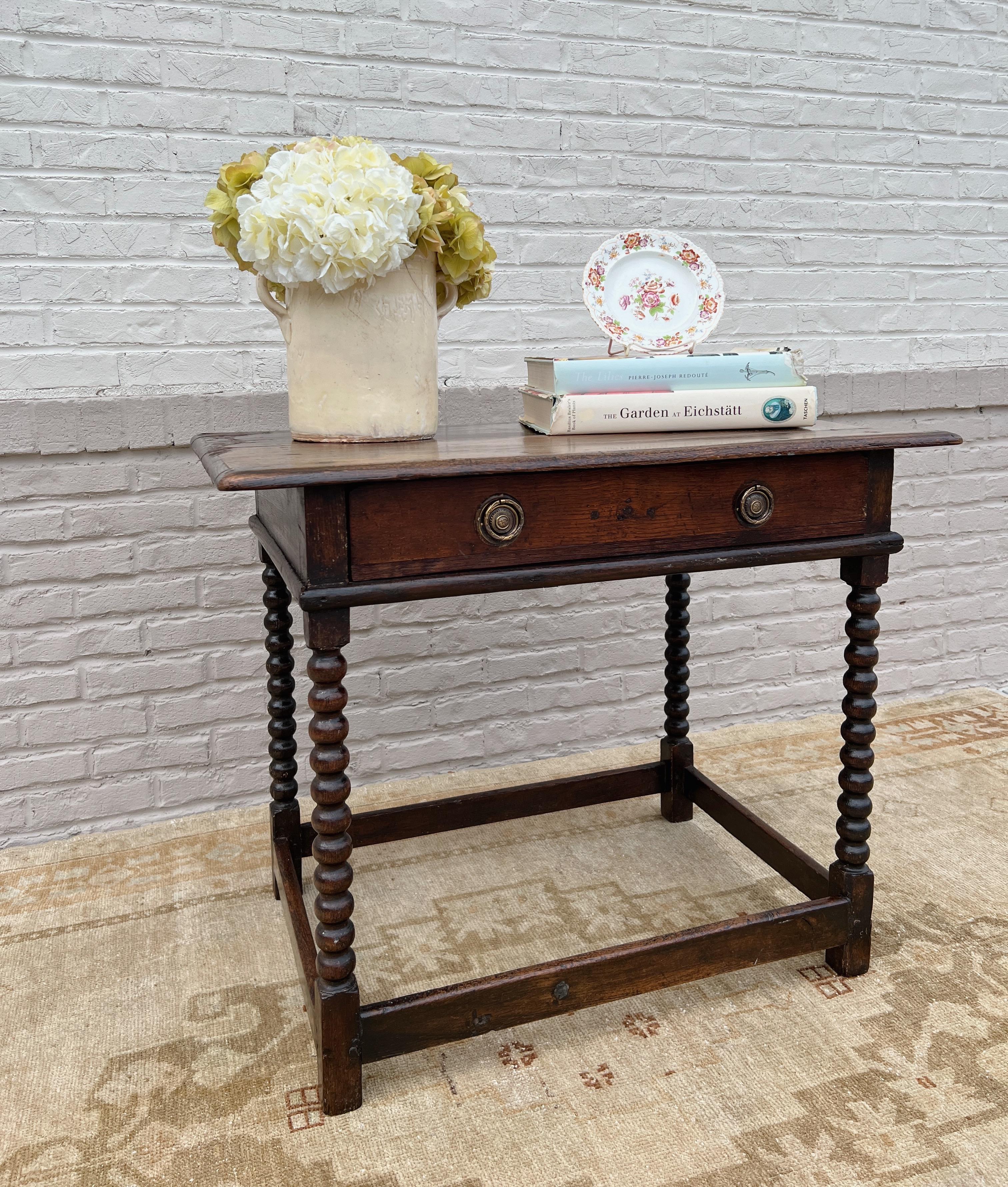 circa 19th century England. 

A beautiful English table that would make a lovely nightstand, end table, or dressing table. Features a molded edge rectangular top over a single drawer with brass hardware. Supported by bobbin legs and box stretcher.