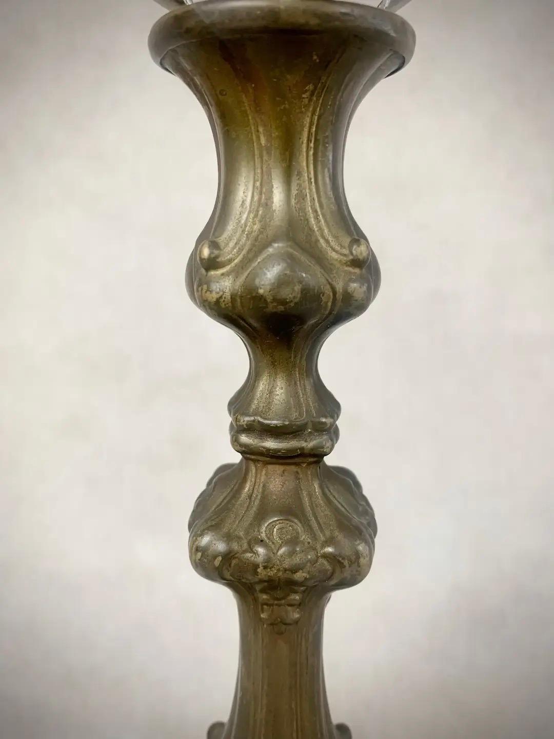 Offering a late 19th century cast brass Rococo style candlestick lamp, circa 1890-1900, featuring a scrolling column form with elaborate, symmetrical details indicative of the Victorian era. Rewired for modern electrical use in the 1950s. Made in