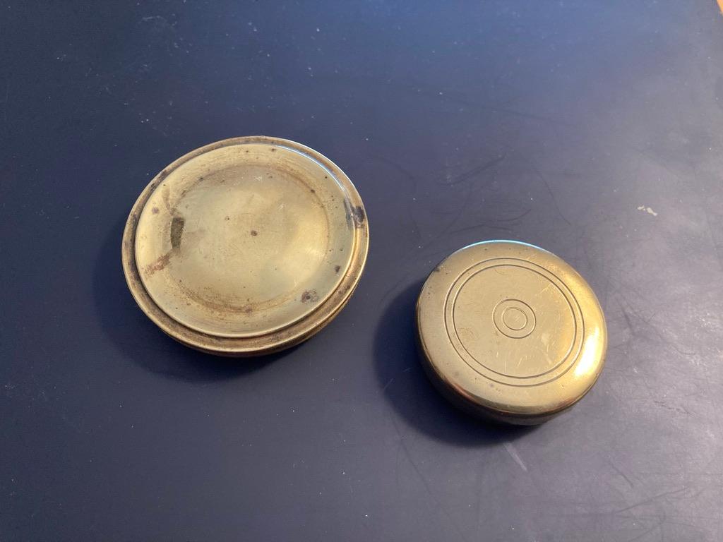 Two English brass pocket box compasses, both with handcrafted cases. The larger with beveled and beaded edges early 19th century. The smaller with incised circular decoration on top, late 18th-early 19th century. Each a little bit of