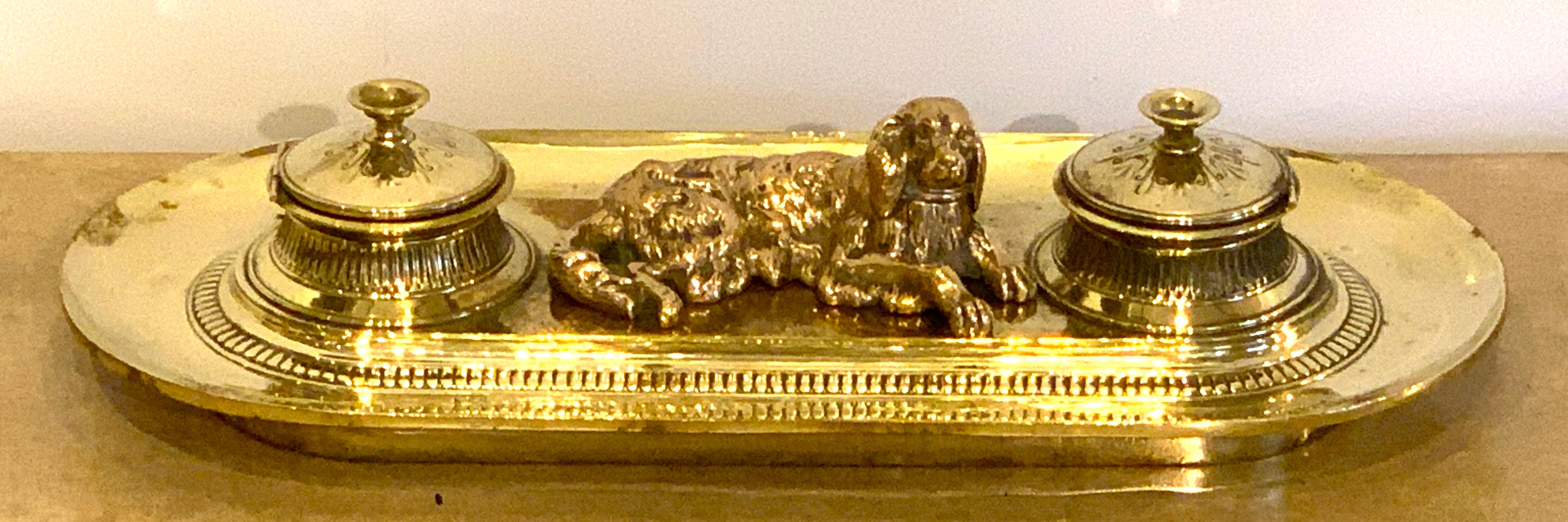 19th century English brass resting dog double inkwell, the wells opening to the left and the right.