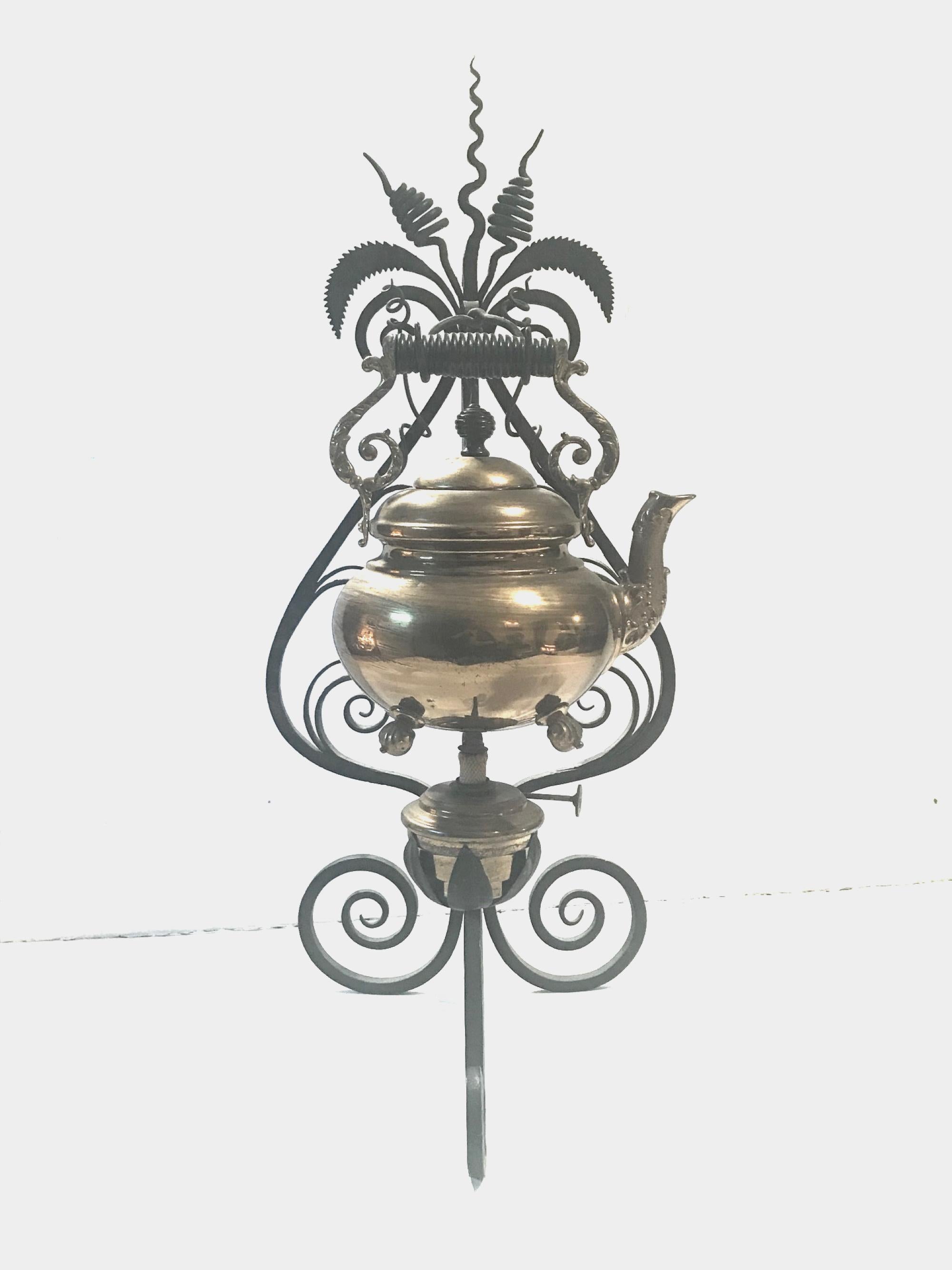 19th century English brass tea kettle warmer rare wrought iron stand.

This tall, Victorian wrought iron stand is a scrolled tripod warmer created with tremendous craftsmanship. The brass kettle is decoratively embossed on the spout and the