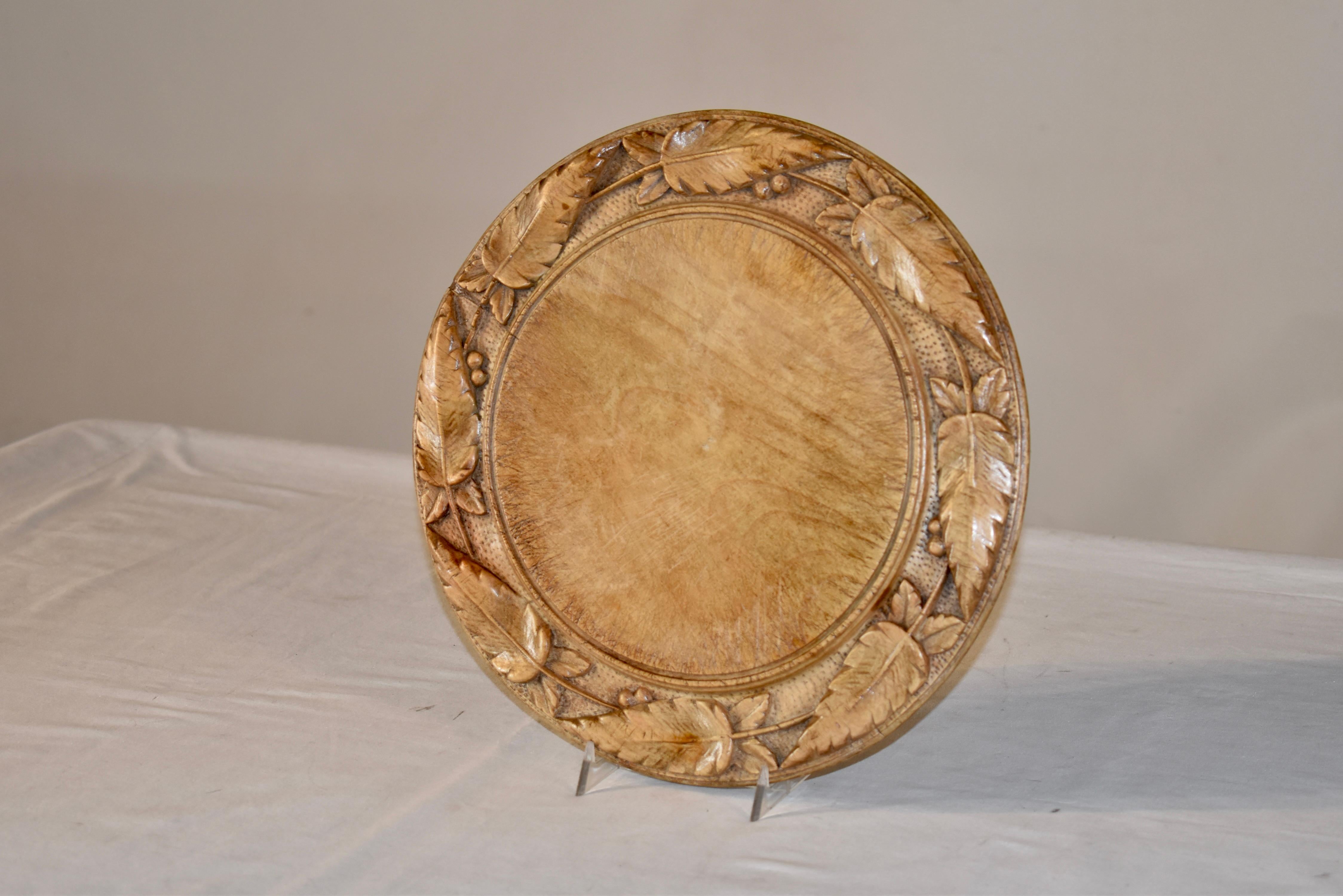 Beautifully hand-carved 19th century bread board made from sycamore.  There is a border around the rim which has lovely hand carving decoration of leaves and a molded edge.  Plate stand not included.