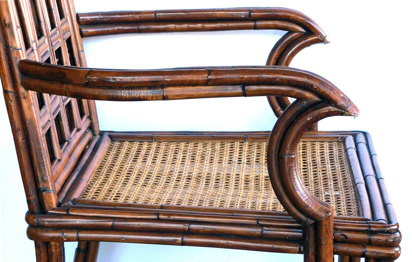 The openwork backrest consisting of three pointed arches above a caned seat flanked by down-scrolled arms; raised on bamboo cluster supports joined by cross stretchers; caning intact; frame structurally sound with some movement.
