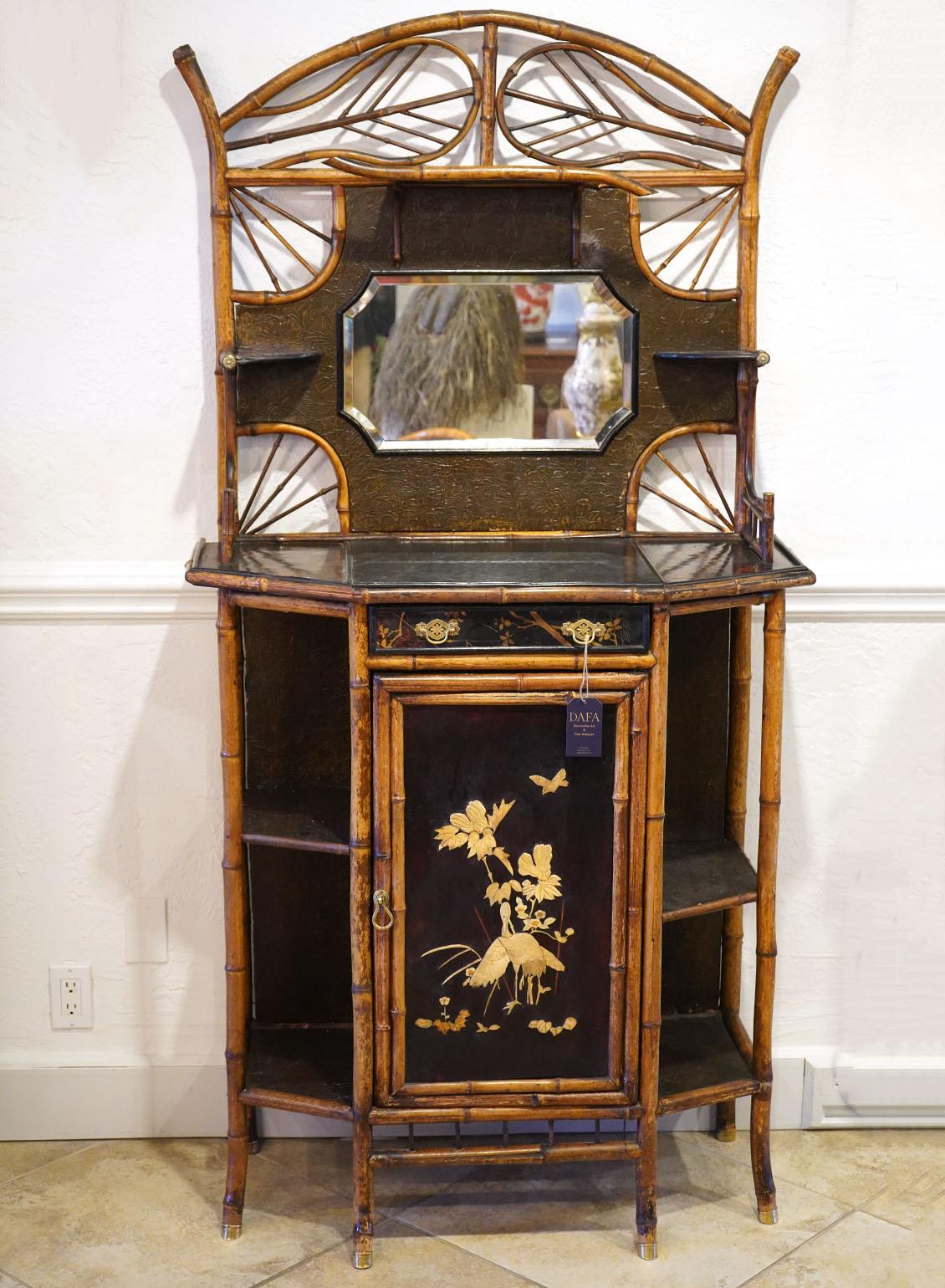 19th Century English Brighton pavilion style bamboo and lacquered cabinet. One drawer and one door flanked by open shelves. Brass cupped feet signed W.F. Needchamp, PAT. Center has a mirror. Applied birds and flowers. 