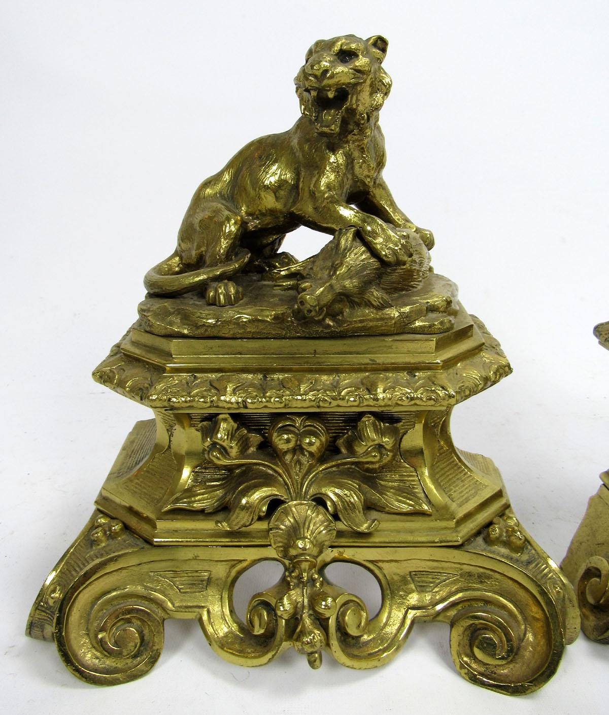 Antique bronze doré figural fire dogs featuring a lion and lioness with their prey.