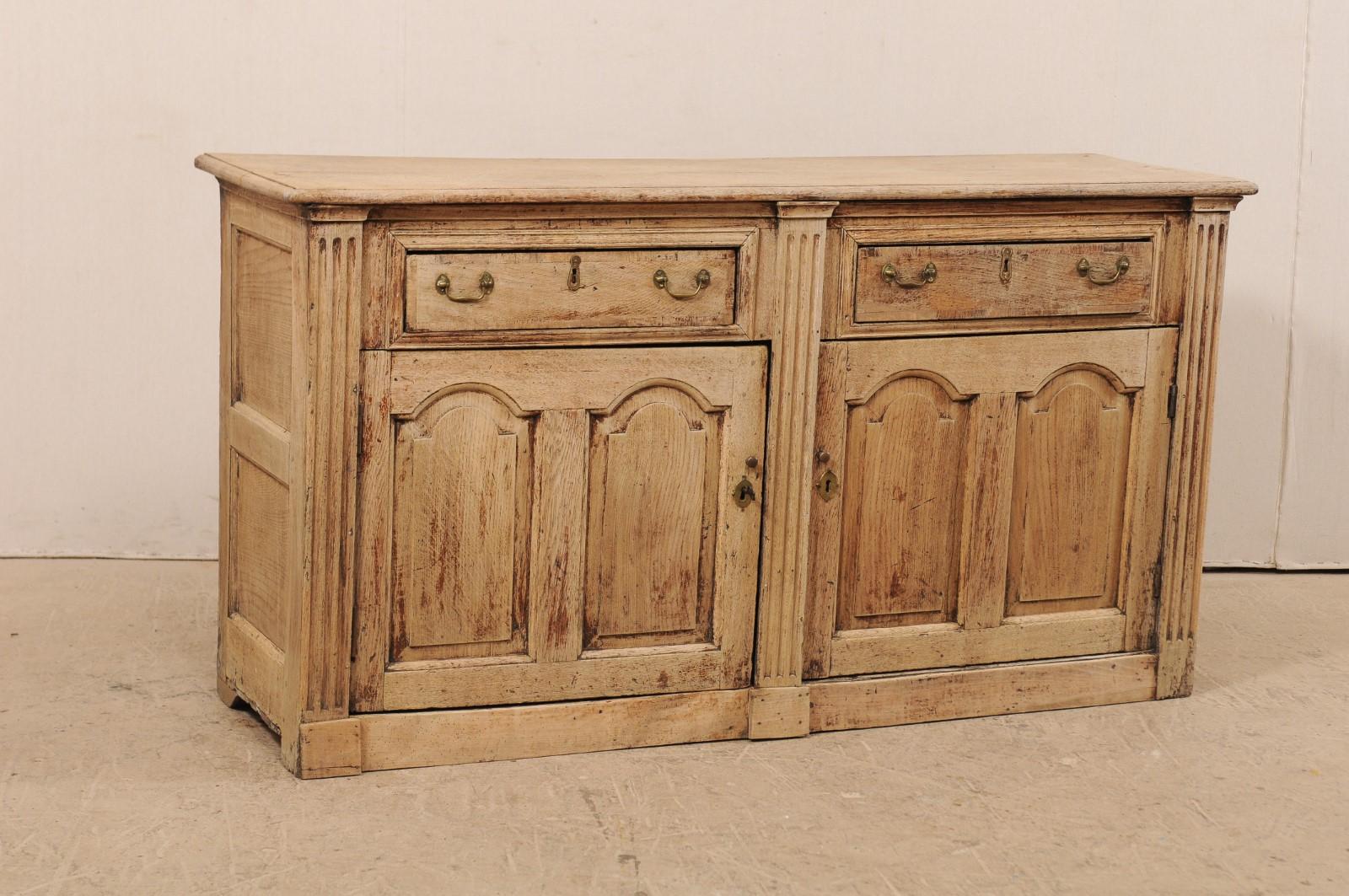 A 19th century English carved wood buffet cabinet with fluted columns. This antique cabinet from England, which is approximately 5.5 feet in length, features a slightly overhung rectangular-shaped top which rests atop a case having two half-drawers