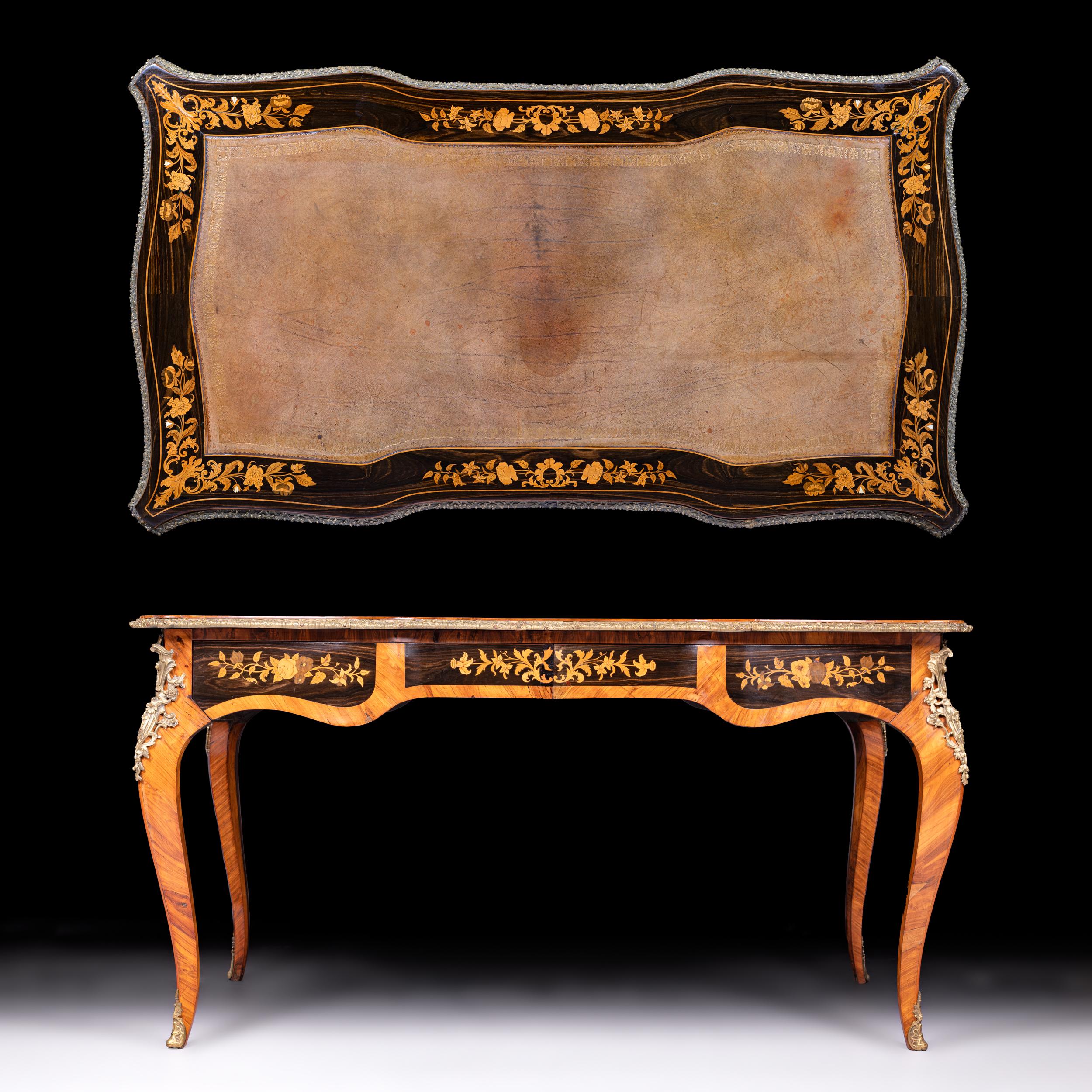 A fine 19th century Louis XV style Walnut, Ebony and floral marquetry Bureau Plat in the manner of Edward Holmes Baldock, the serpentine shaped top inset with a panel of tooled leather within a border of scroll work and floral trails, the corners