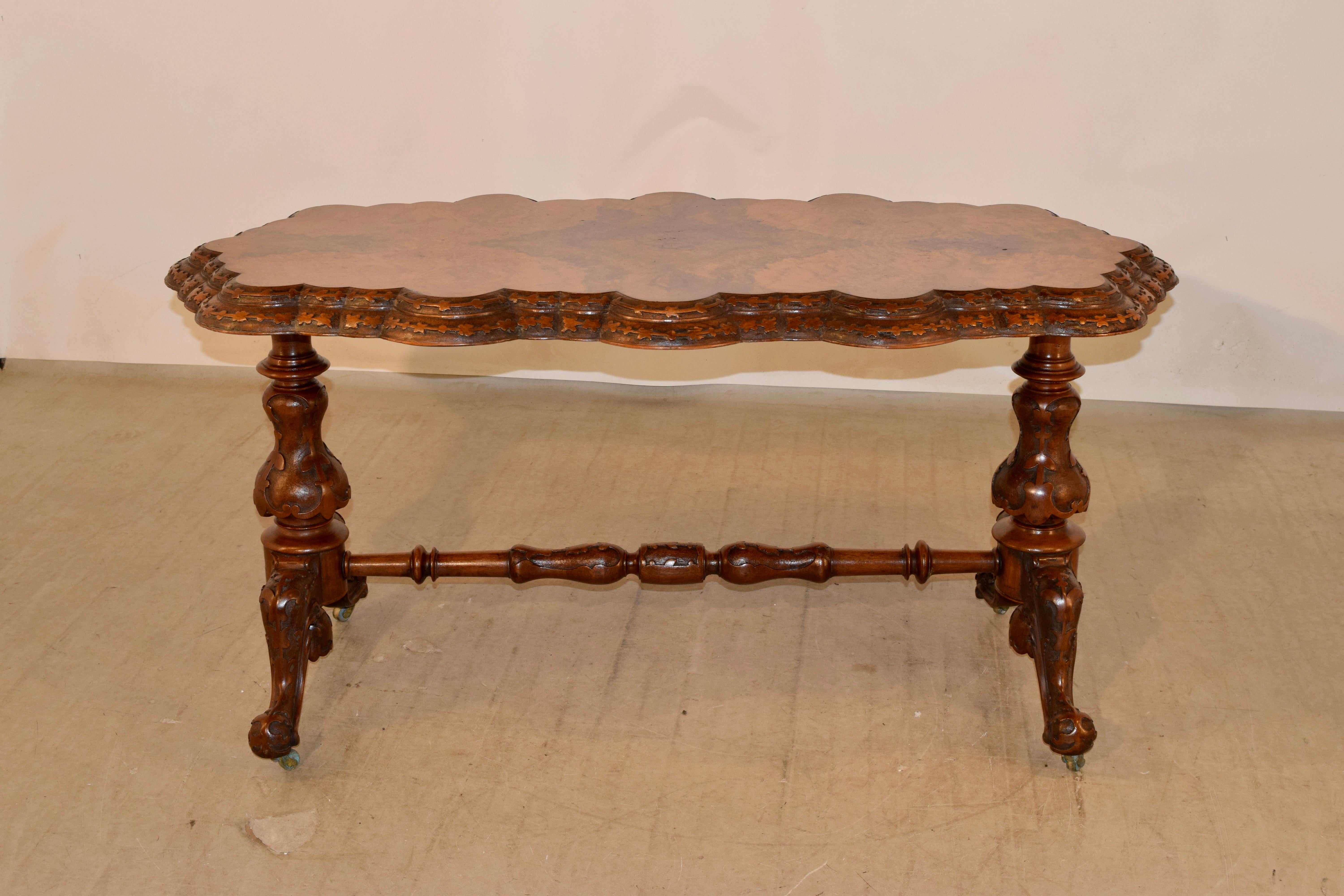 Superb quality late 19th century burl walnut stretcher table with a double beveled, scalloped and relief carved edge. The top is exquisitely grained - an absolute show stopper! The legs are also relief carved decorated pedestals, joined by a hand