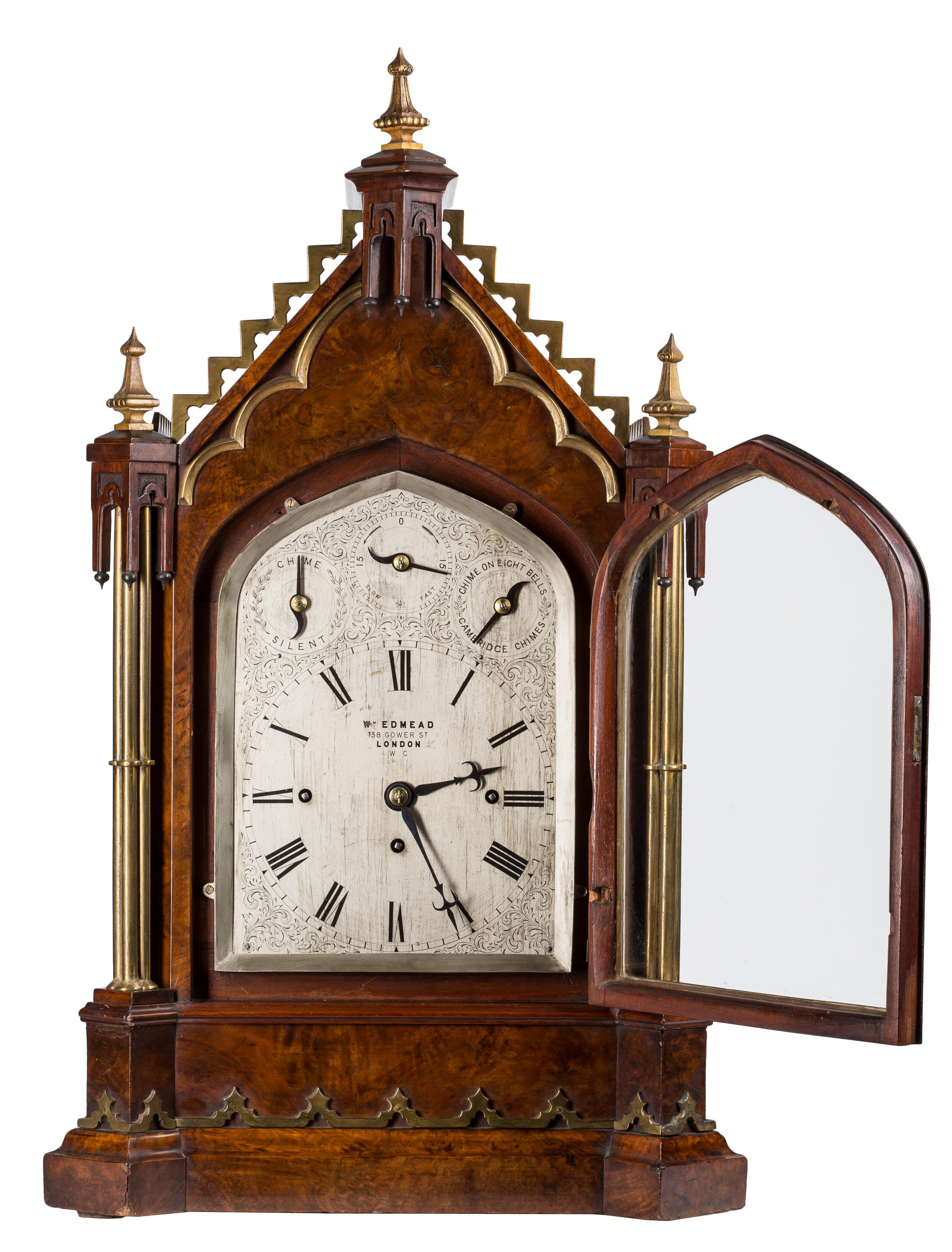 A 19th century English Victorian Gothic Revival mantel clock with dramatic architectural silhouette, reminiscent of a Gothic cathedral complete with spires, pinnacles, columns and pointed arches. Richly-grained burl wood contrasting with sculptural